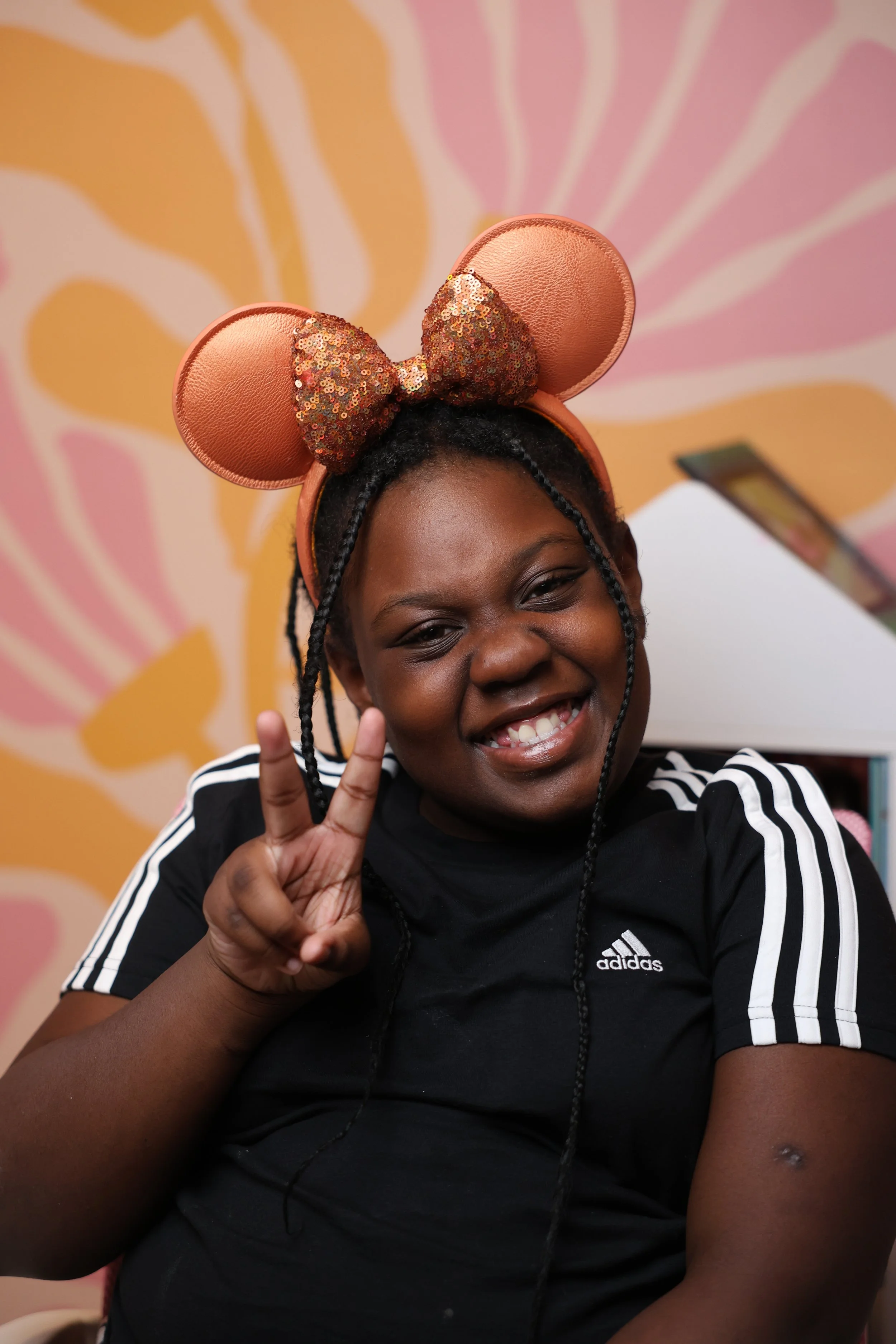 one of camp attendees smiling for a photo wearing coral mickey ears