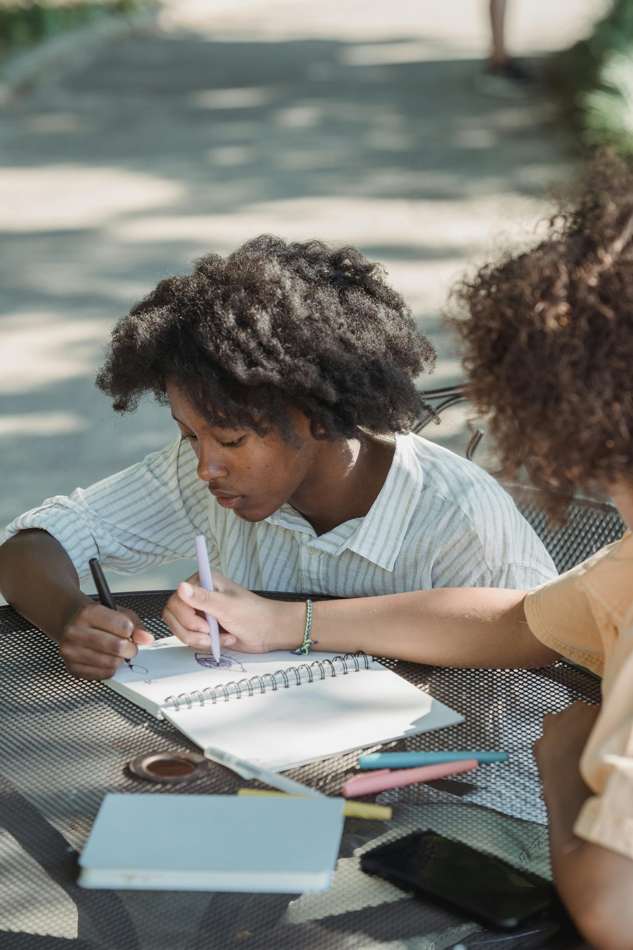 girls drawing on a notepad outside