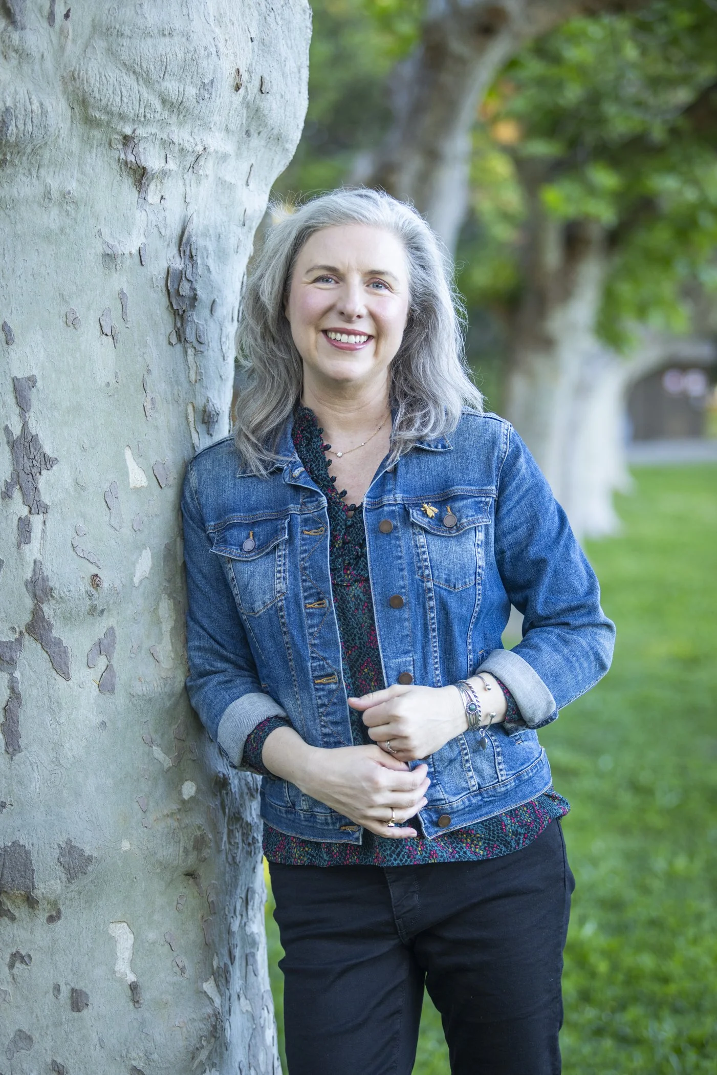 Dr. Teresa Matazzoni outdoors, wearing a denim jacket and smiling at the camera.