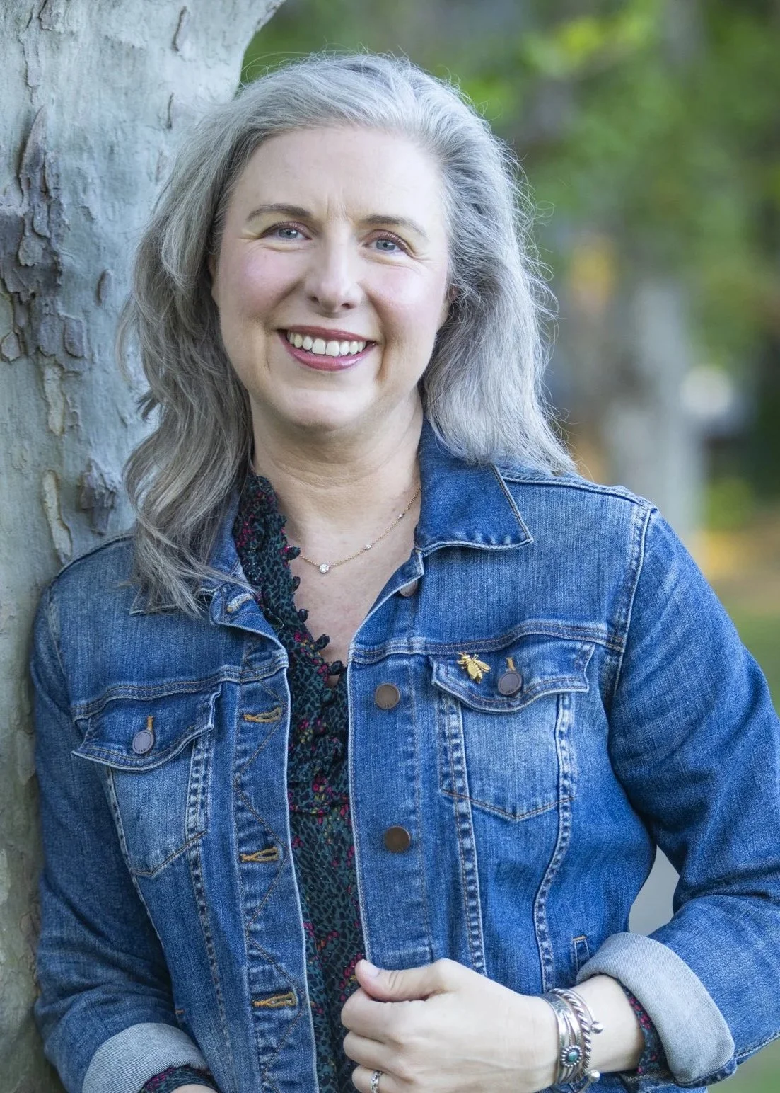 Dr. Teresa Matazzoni outdoors, wearing a denim jacket and smiling at the camera.