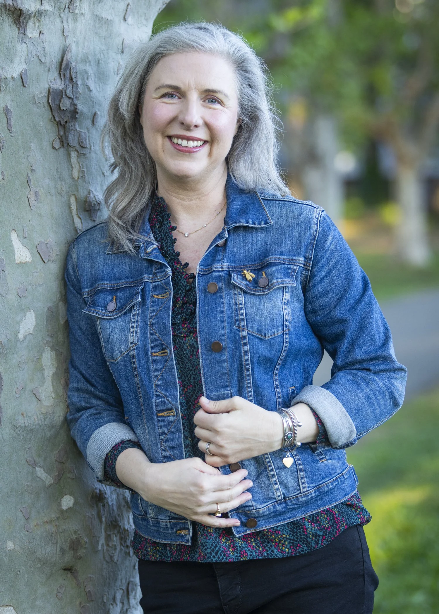 Dr. Teresa Matazzoni outdoors, wearing a denim jacket and smiling at the camera.