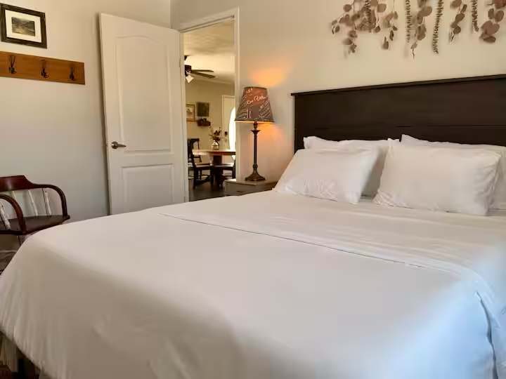 Clean, neatly made bed with white linens and pillows in a cozy bedroom.