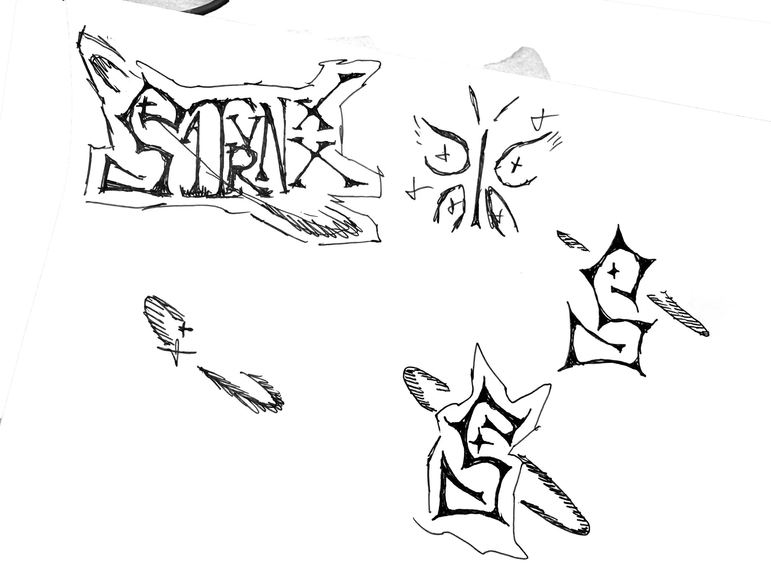 Hand-drawn sketches of rectangular tags with stylized text, surrounded by decorative elements, on white paper.