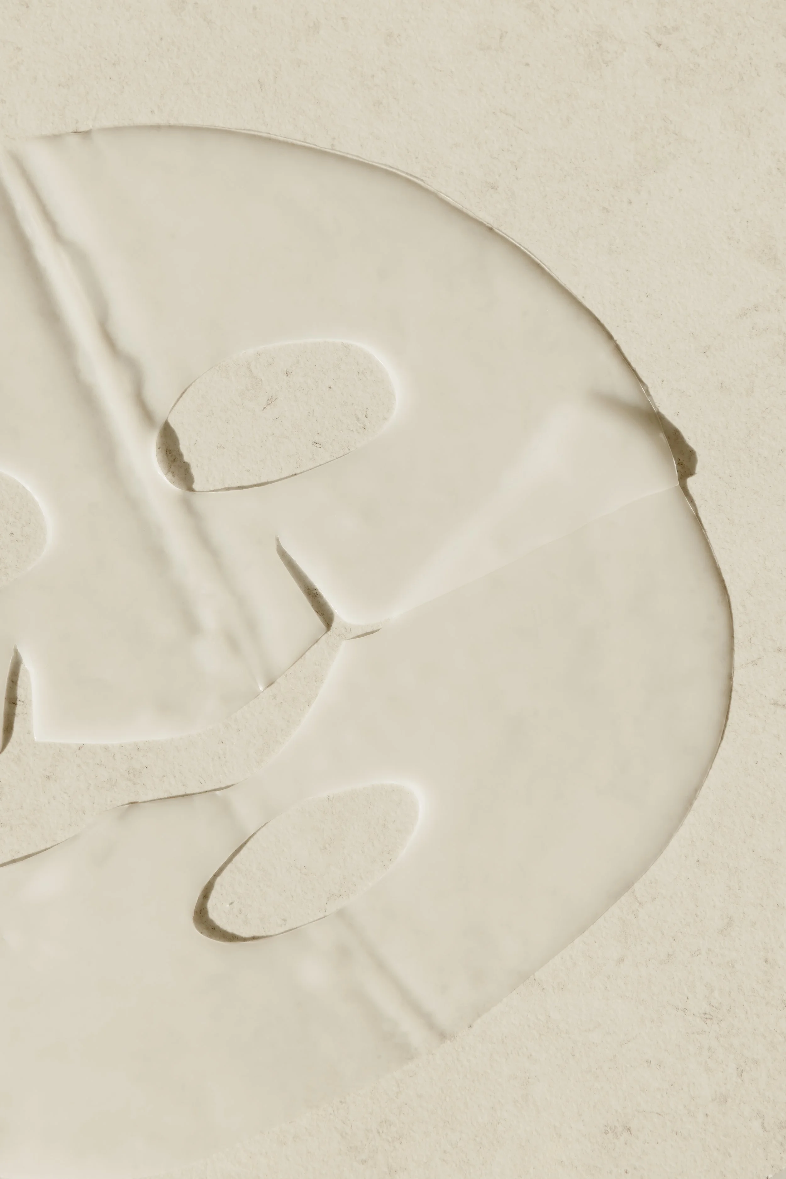 Close-up of a white paper cutout with intricate cut-out patterns, laying on a matching white textured surface.