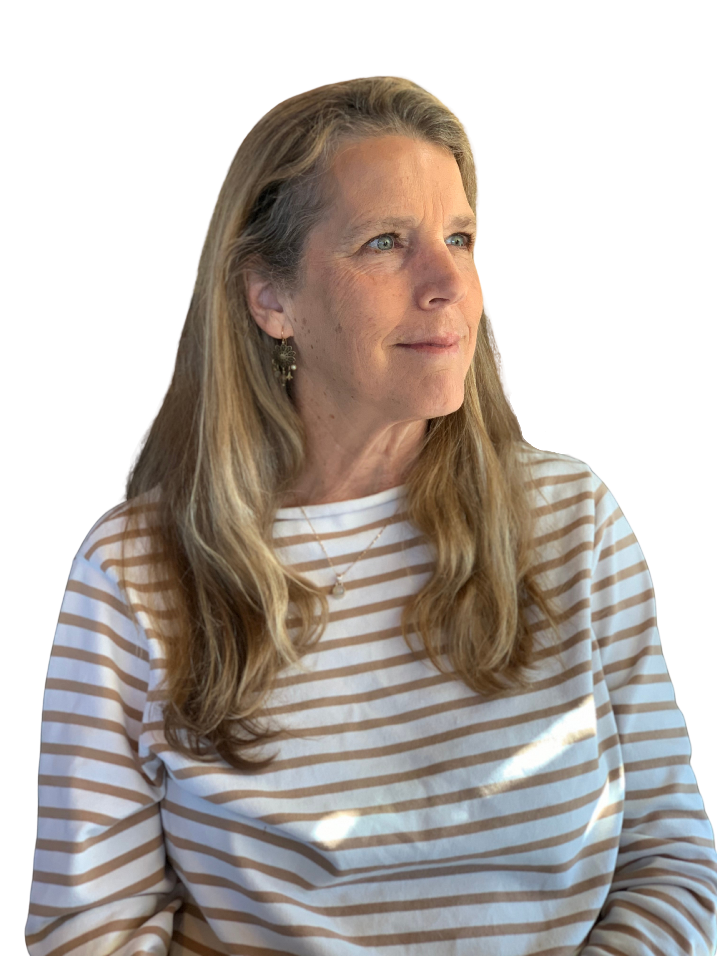 A woman with long, wavy blonde hair and blue eyes, wearing a white and tan striped shirt, standing outdoors with sunlight on her face.