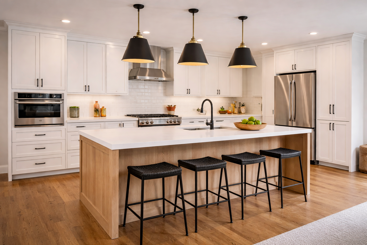 Modern kitchen with white cabinets, stainless steel refrigerator and oven, black pendant lights over island with white countertop, wooden base, four black stools, hardwood floor, and decorative items and fruits on counters.