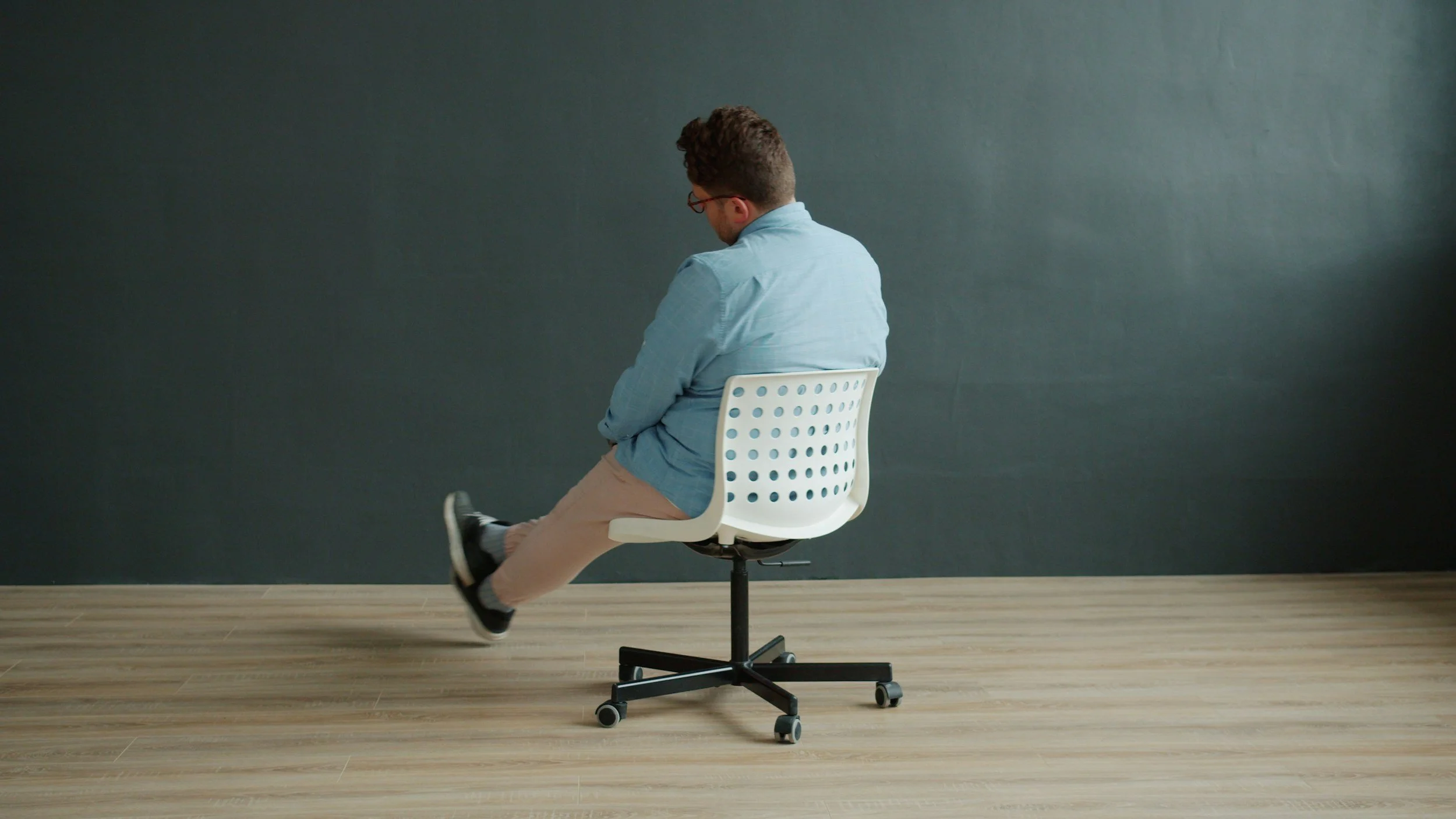 A person stretching one leg while seated in an office chair.