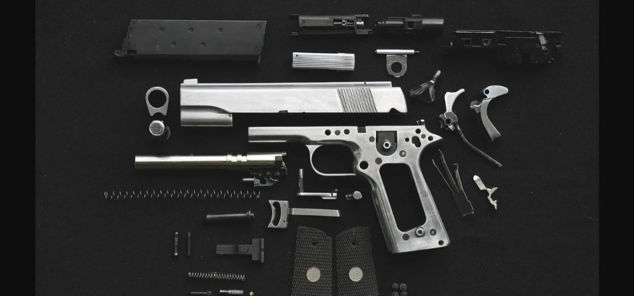 Disassembled semi-automatic pistol parts on a black background.