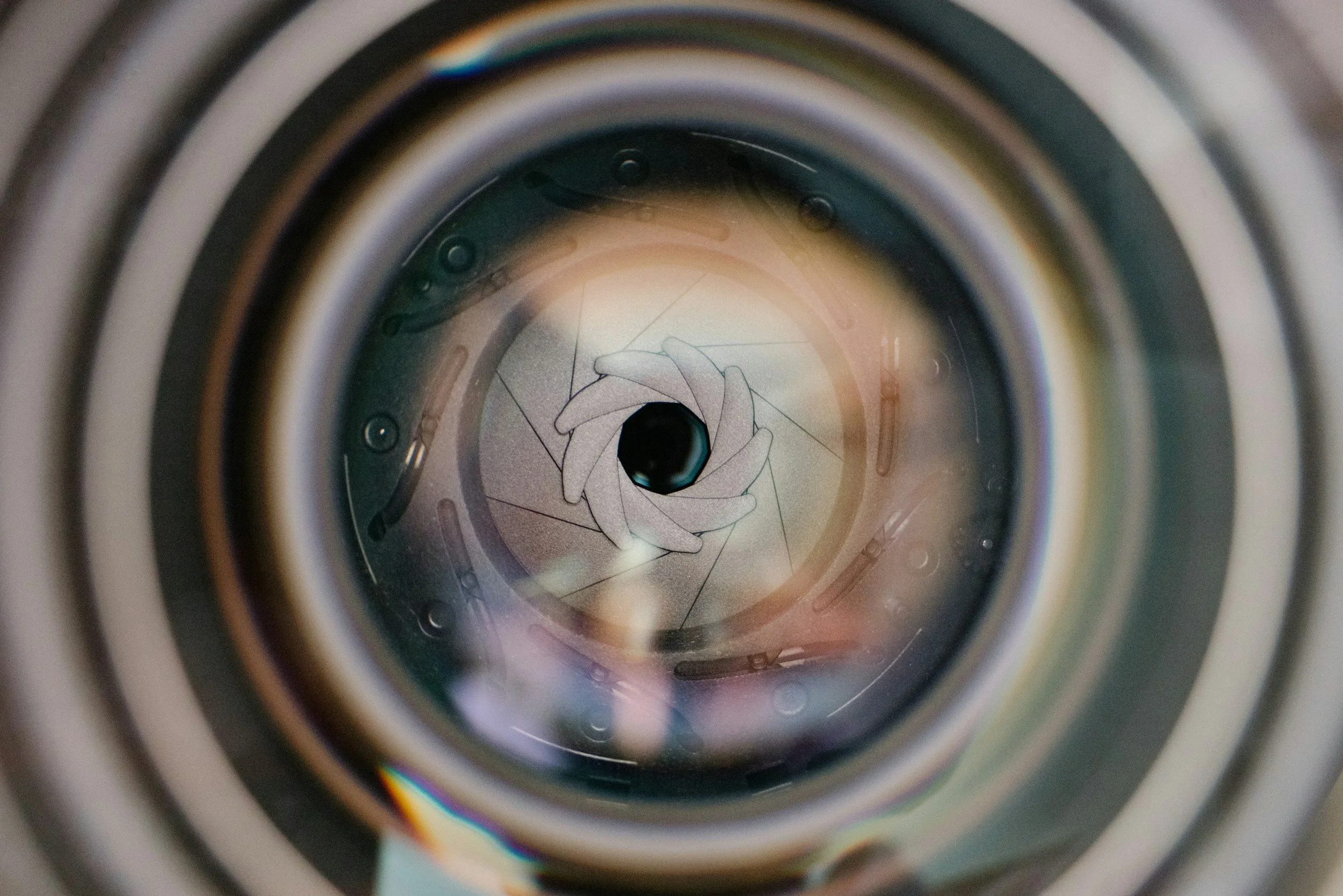The image shows the inside of a camera lens, looking towards the camera's sensor, with some artistic sketches of a hand and eye visible through the lens.