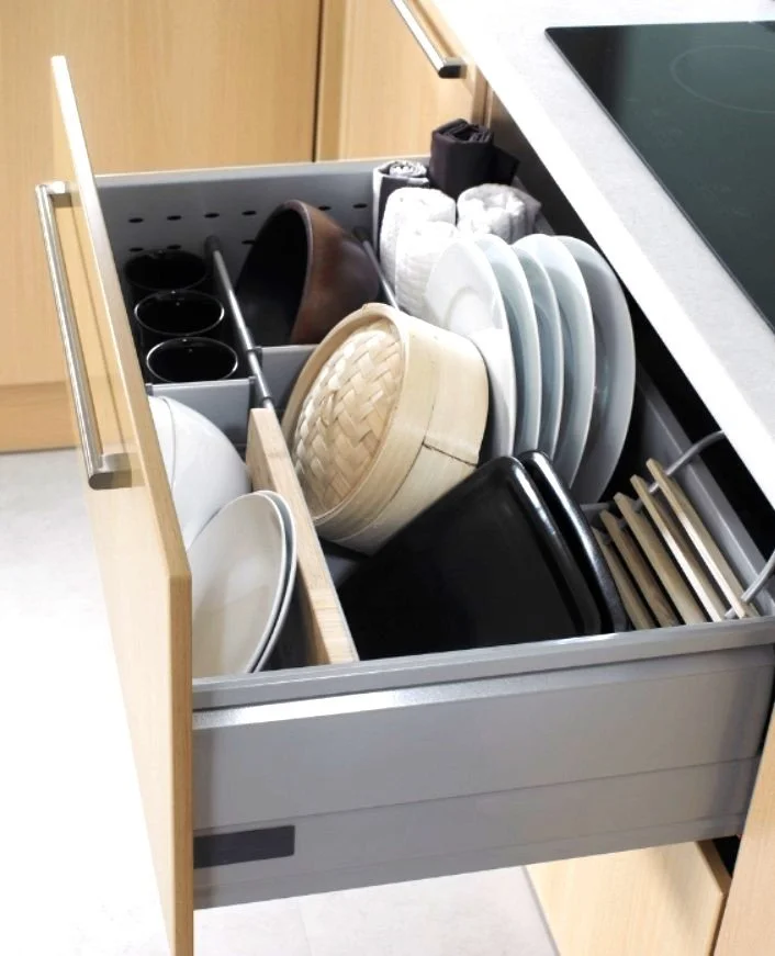 Kitchen drawer containing various plates, bowls, mugs, and utensils, organized in compartments.