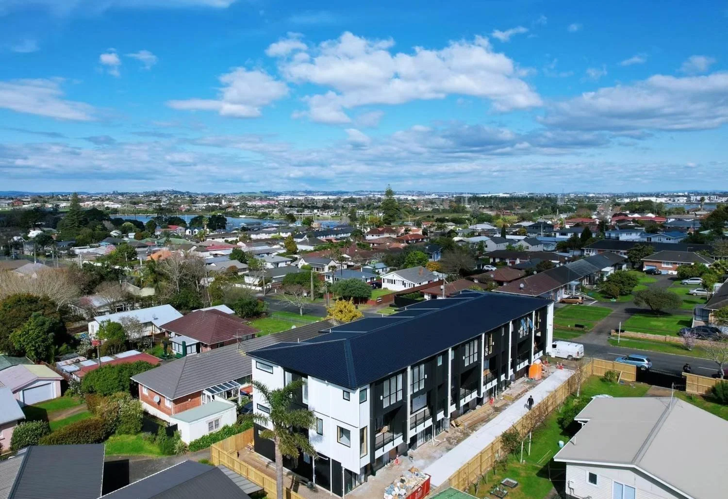 Aerial view of a new multi-unit residential property development under construction in Panmure, Auckland. The modern black-and-white building stands out among traditional neighbourhood homes.