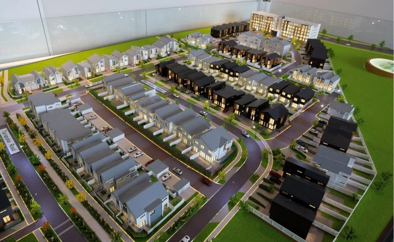 Illuminated architectural scale model of a master-planned residential development, showcasing modern new-build townhouses, streets, and landscaped green spaces in Westgate, Auckland.