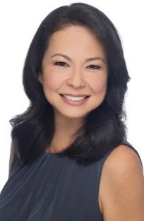 A smiling woman with shoulder-length dark hair wearing a dark sleeveless top.