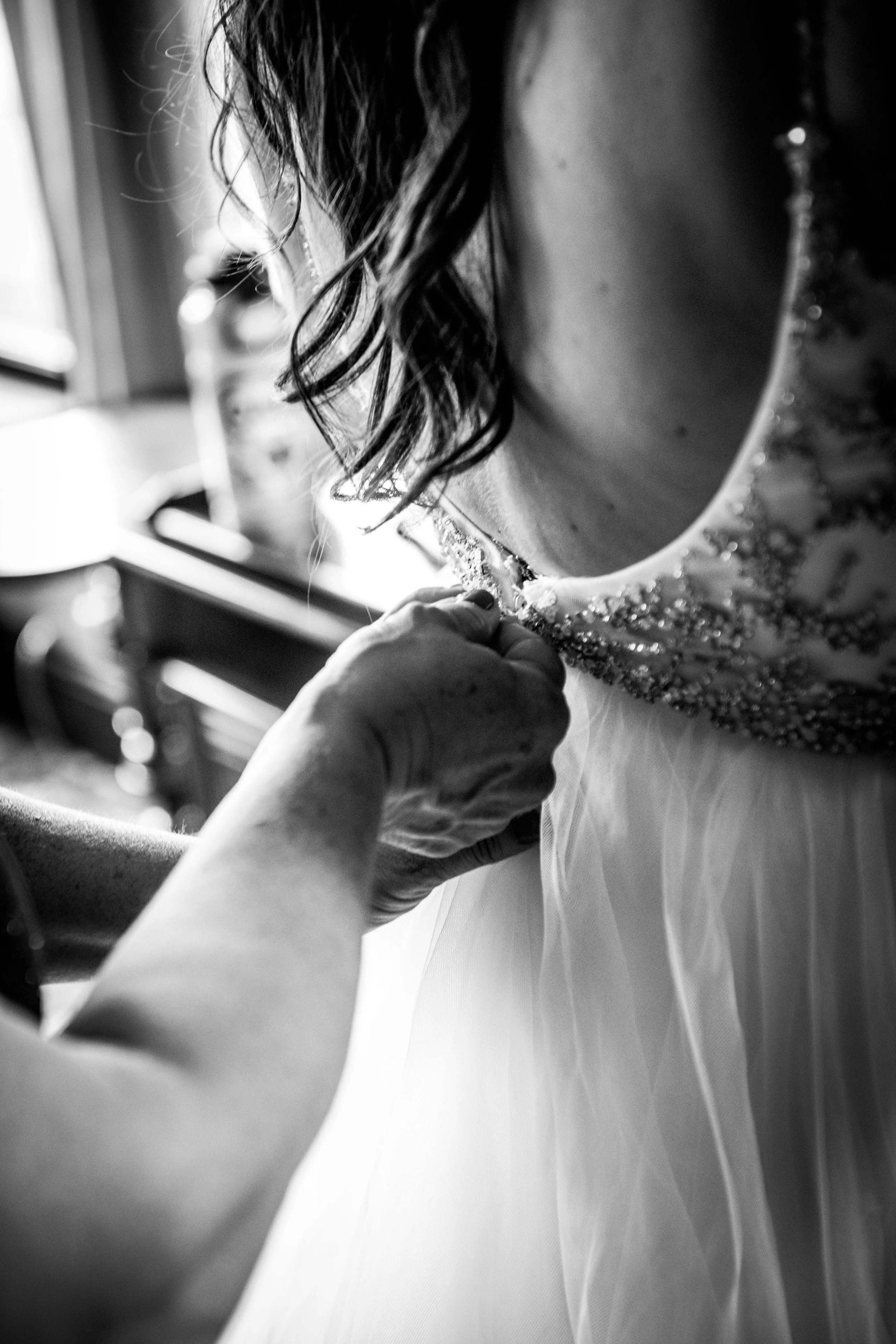 A person adjusting the neckline of a wedding dress, with focus on the dress's beaded and sequined collar.