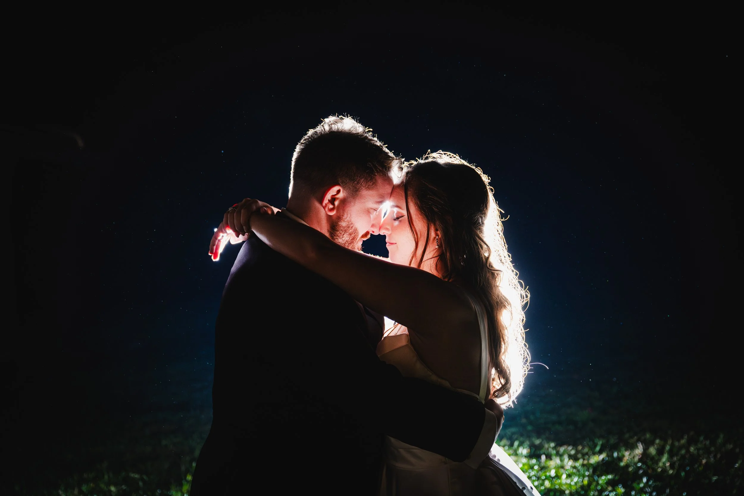 A romantic couple embracing at night with a dark sky and stars in the background.