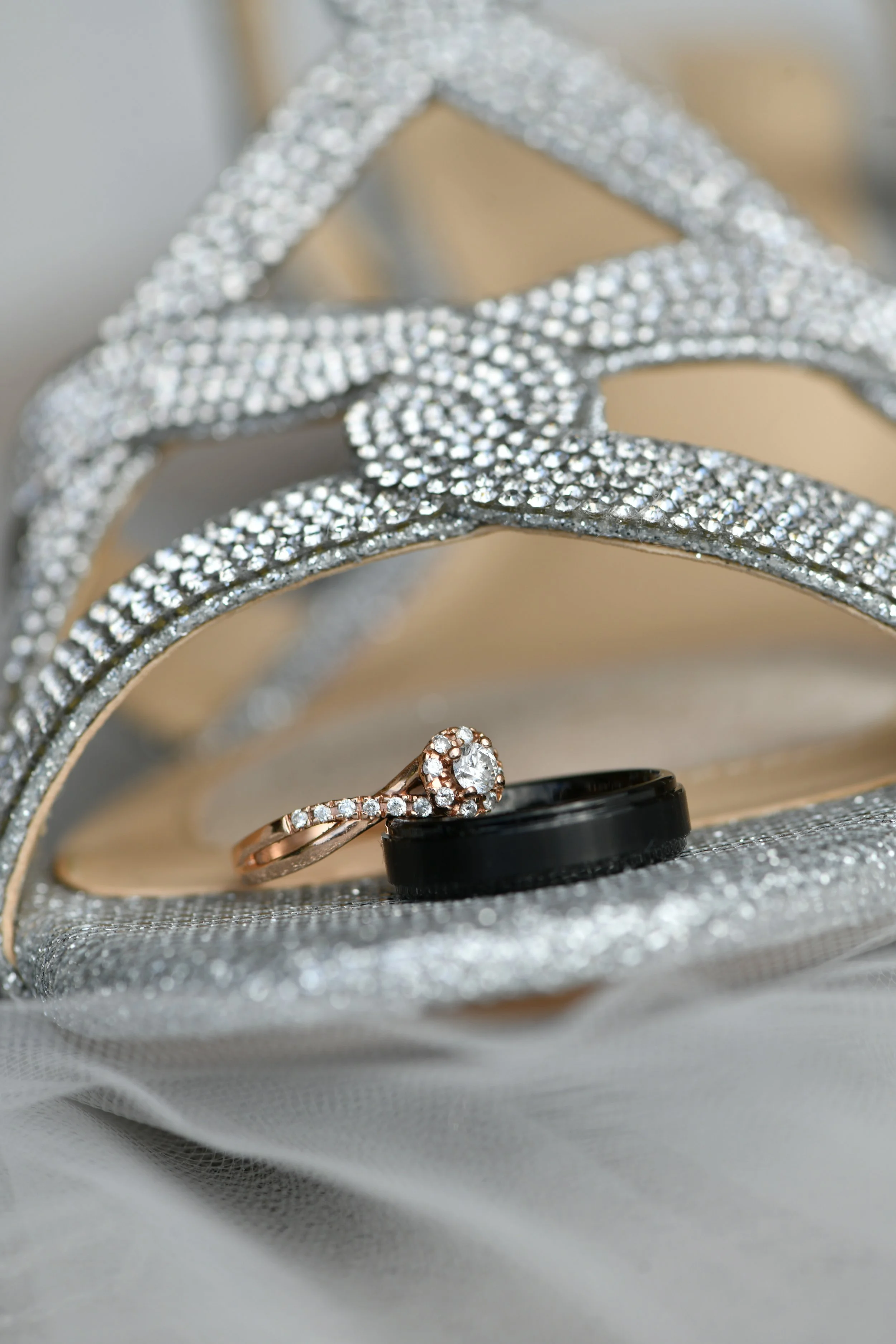 Close-up of a sparkling silver clutch purse with a diamond engagement ring and a black ring inside. The purse is made of glittering rhinestones with a decorative clasp.