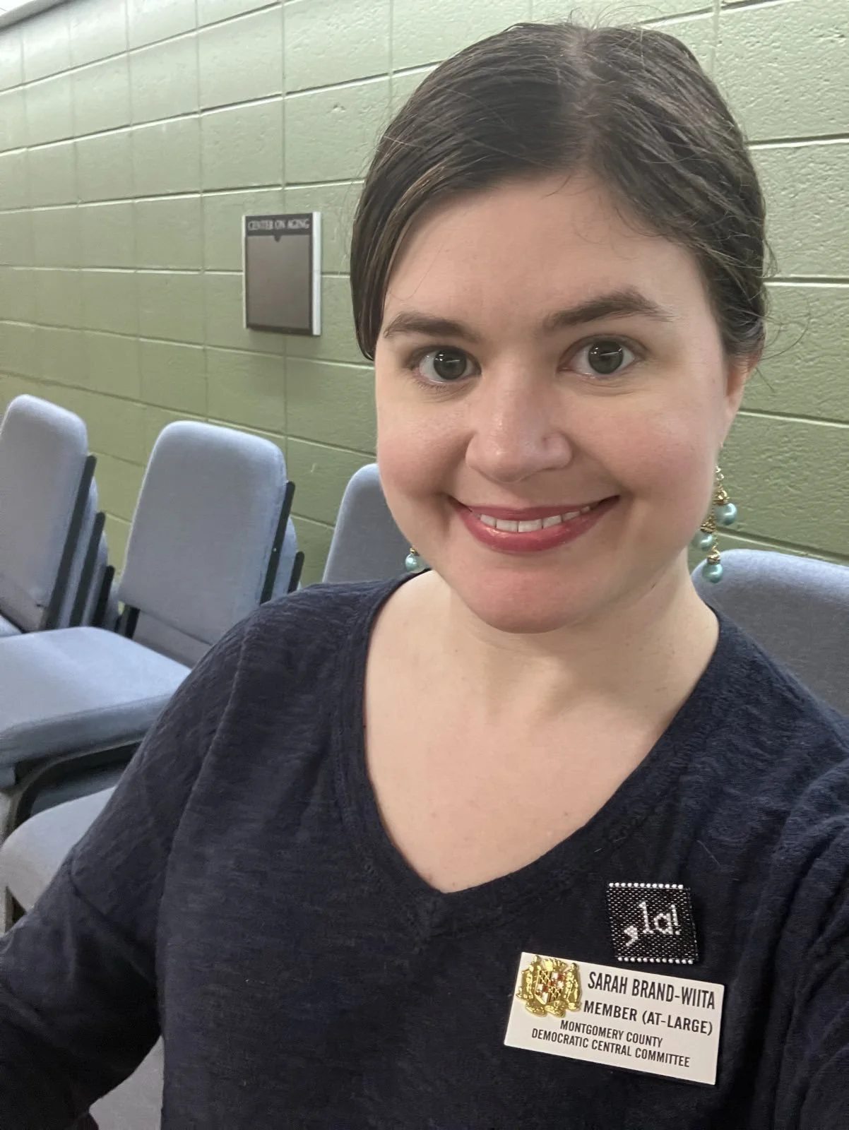 In the MCDCC office, wearing my official MCDCC badge and a pin handmade by one of our precinct leaders that says ",la!" (Try saying it out loud.)