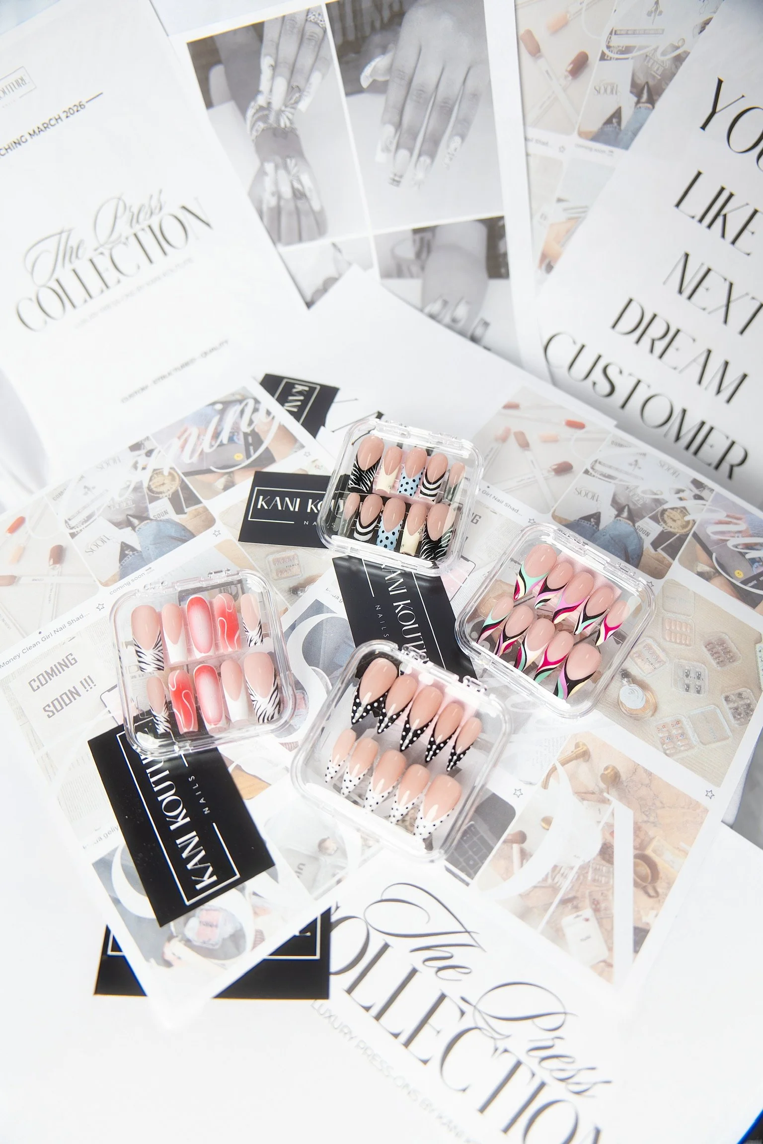 Collections of colorful artificial nails in plastic cases, surrounded by promotional flyers and magazine pages about nail art and beauty.