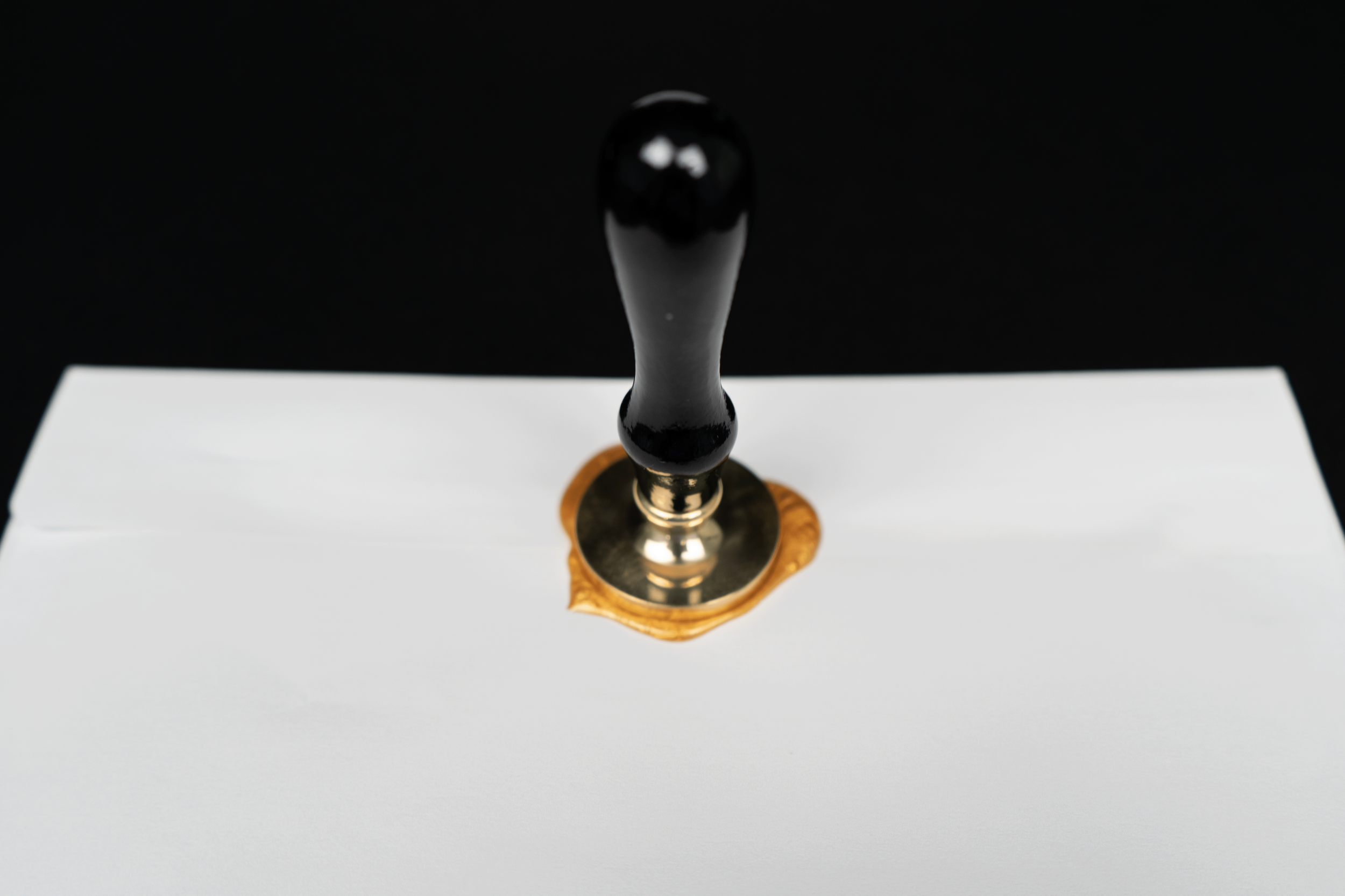 A black rubber stamp pressed onto a white paper, creating a seal with a golden border.