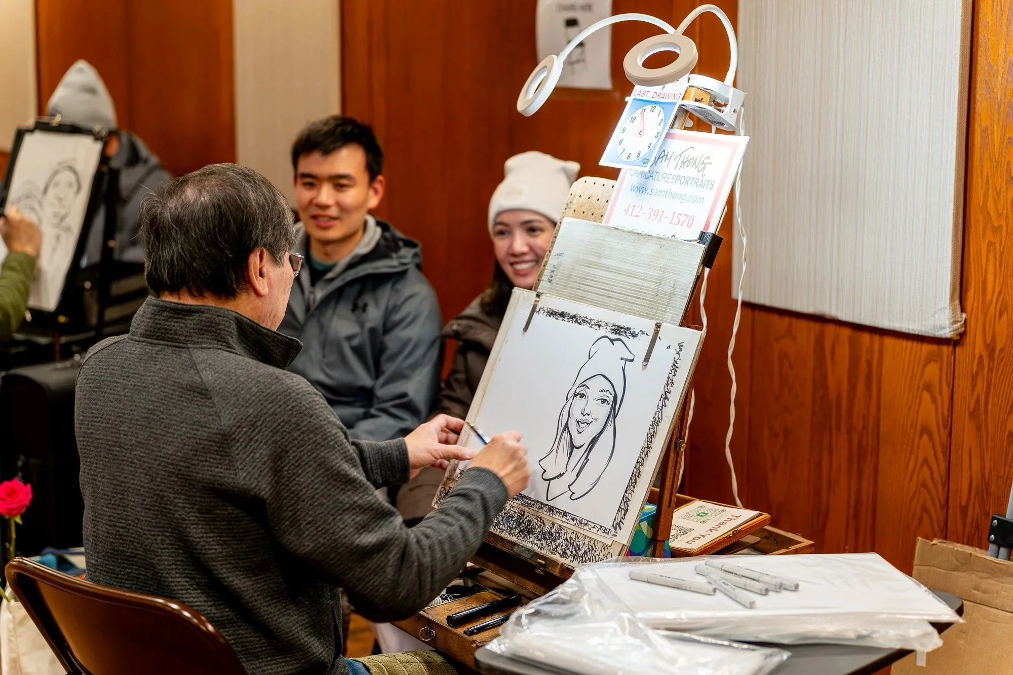 Caricature artist draws a couple who smile in the background