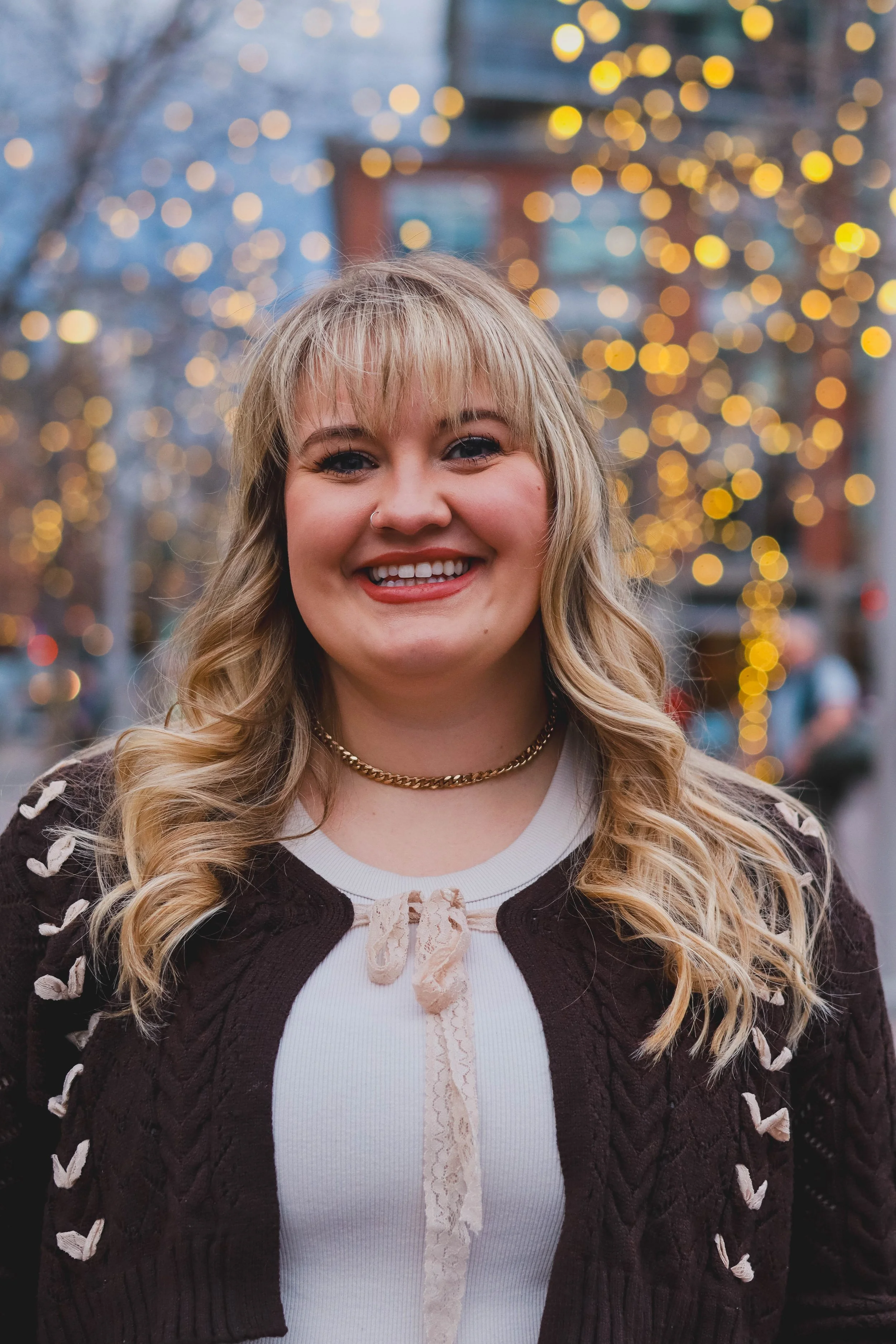 Bailey Robinson, co-founder and Clinical Director of Rooted in More, smiling in front of a warm bokeh light background.