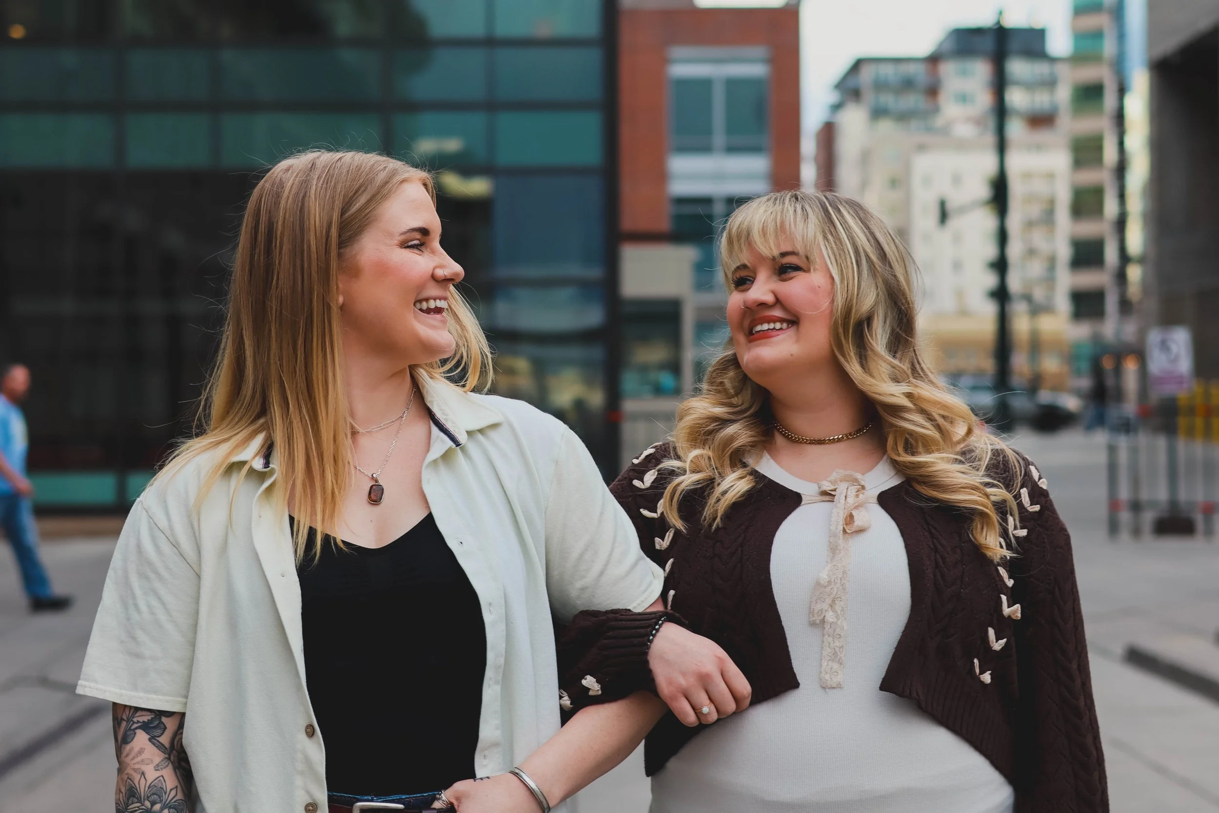 Two women laughing and looking at each other on a city street.
