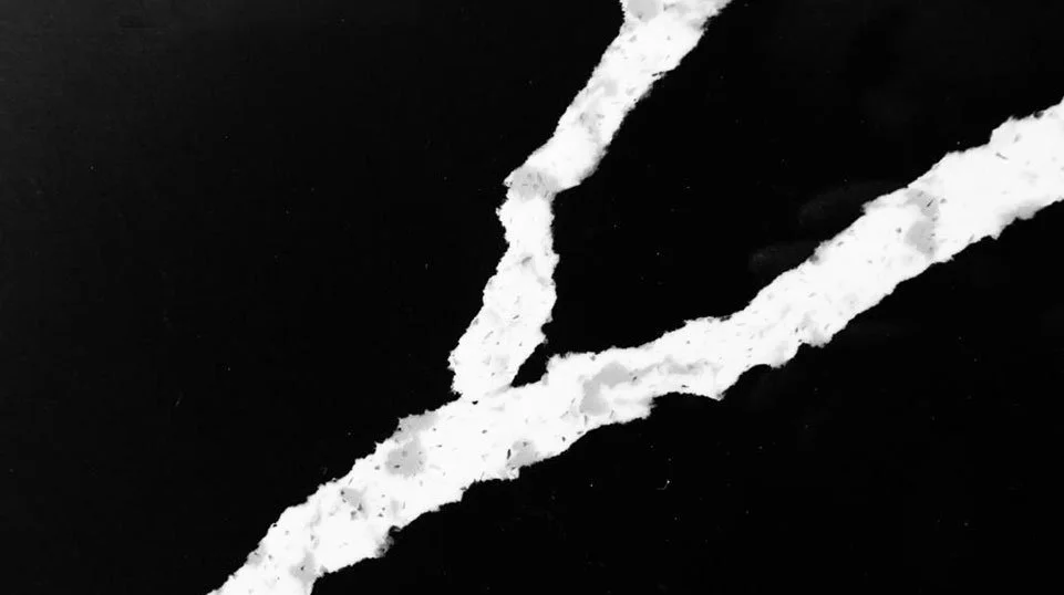 Trozos de papel rasgado en forma de líneas blancas sobre un fondo negro.