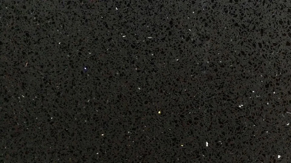 Superficie negra con textura porosa y pequeñas partículas dispersas.