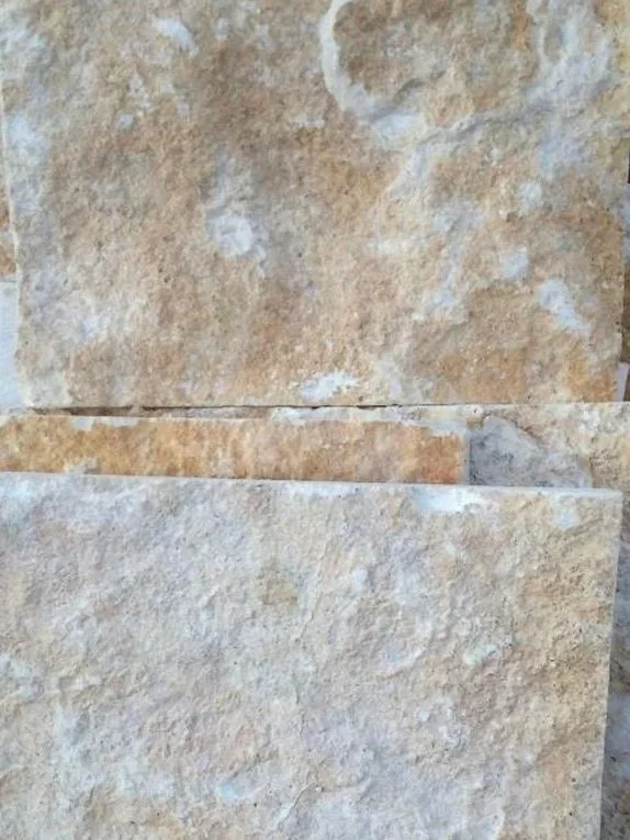 Pared de piedra arenisca con textura rugosa y colores en tonos beige y marrón.