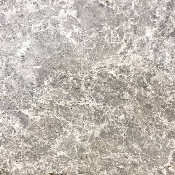 Superficie de piedra o mármol de color gris con vetas blancas y detalles en tonos oscuros.