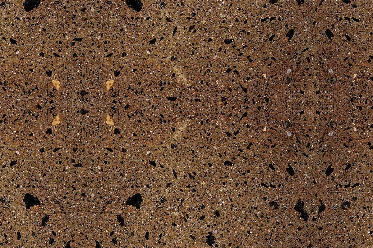 Superficie de piedra o granito de color marrón con vetas negras y pequeñas incrustaciones blancas.