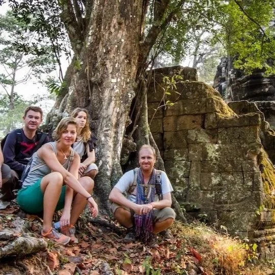 Dry landscape with sparse vegetation, small plants and bushes, with hills or mountains in the background under a partly cloudy sky.