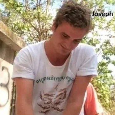 A young man with short dark hair wearing a white t-shirt outdoors with trees in the background. The name 'Joseph' is written in the top right corner.