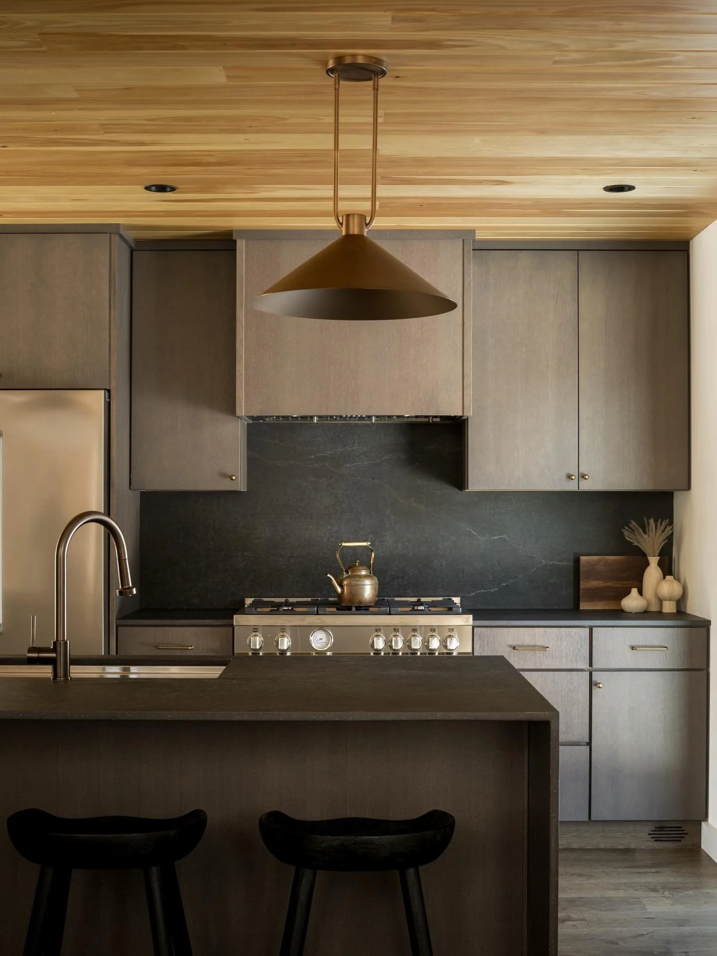 Okemo Mountain House | The elevated form gives way to an open living level organized along the outward edge of the volume. Kitchen, dining, and living align toward the tree line, with glazing extending the space laterally and upward to a double-heigh