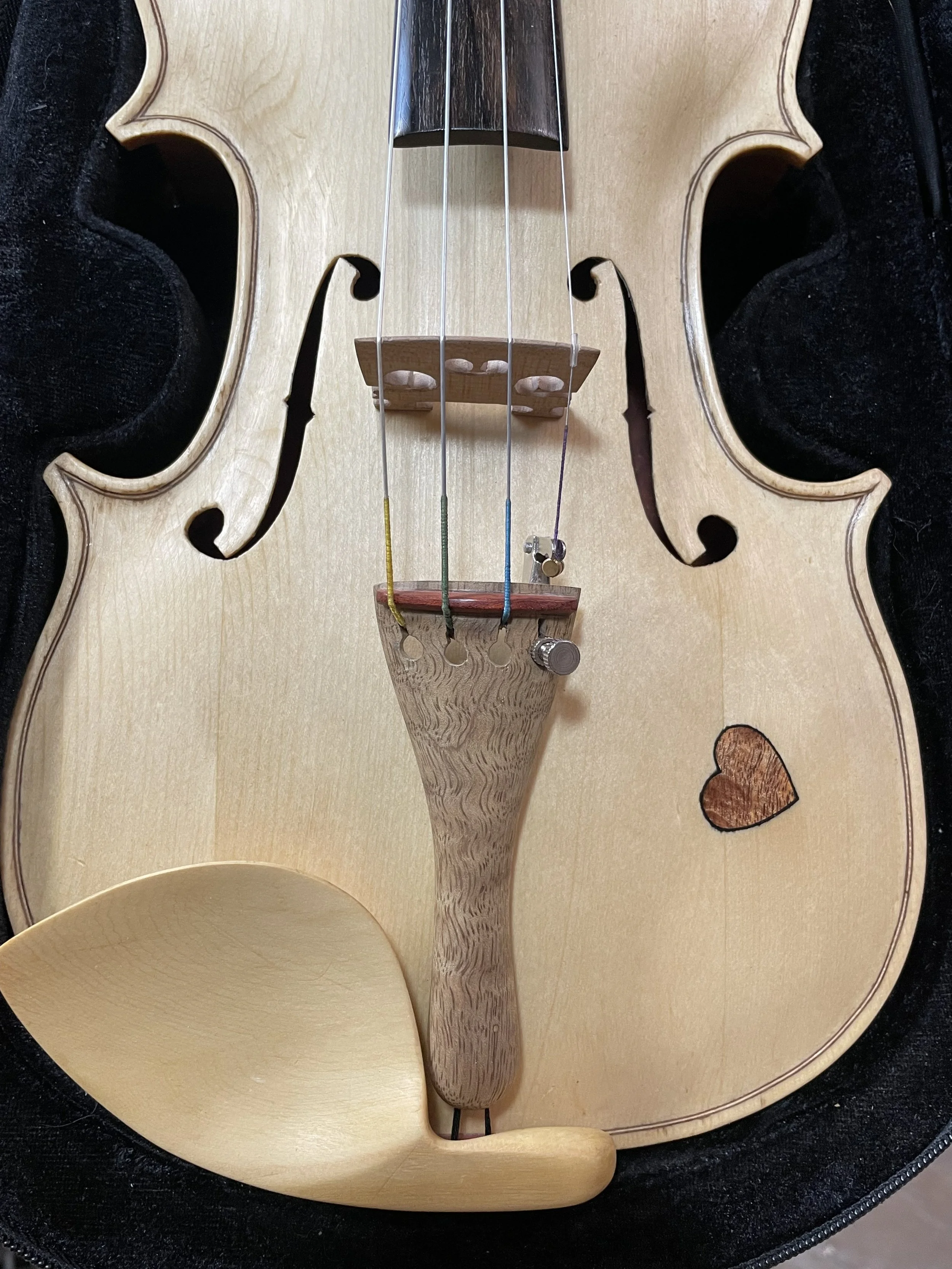 At the lower front, bridge, tailpiece, and chinrest bring the acoustic center into view, where function and material richness meet.
