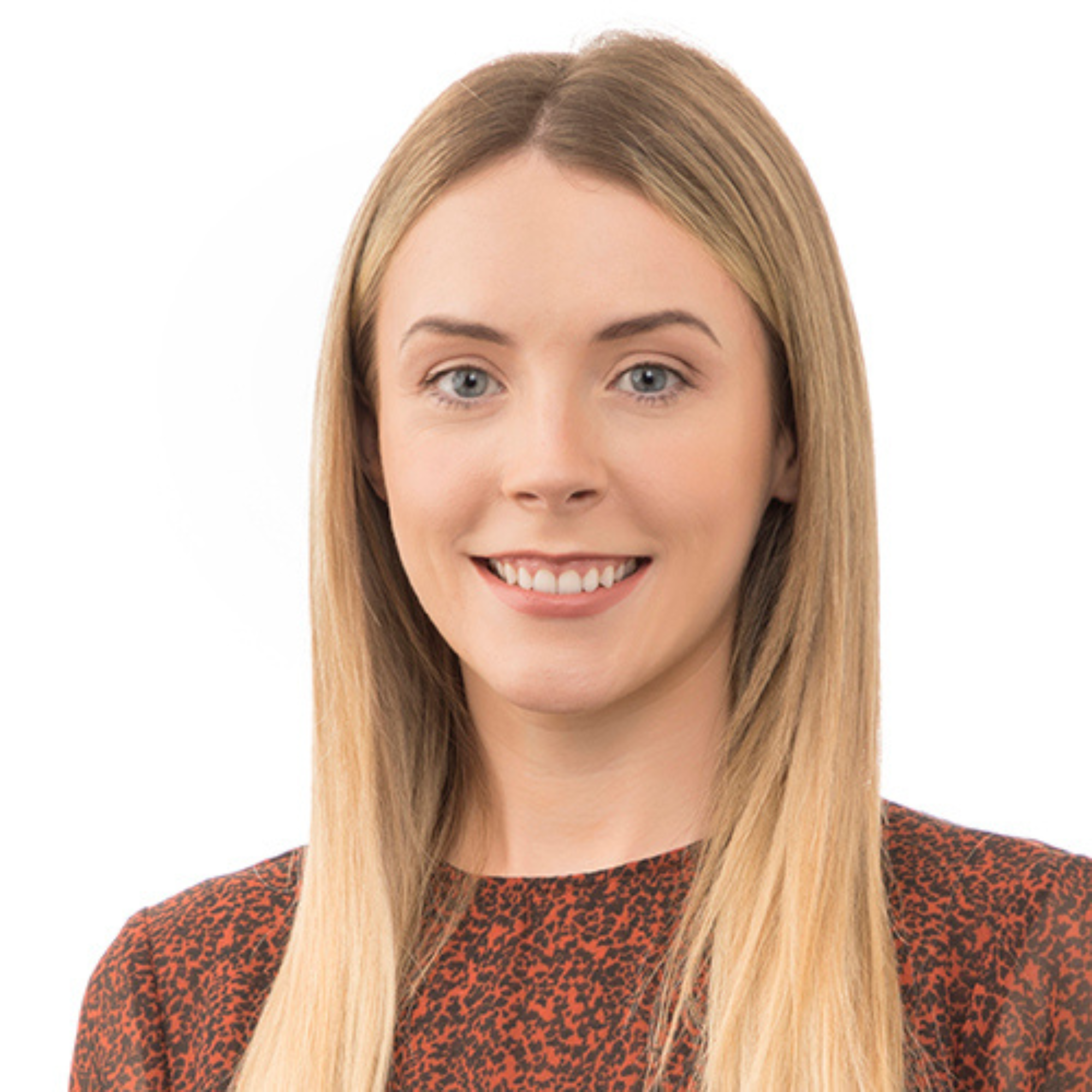 Portrait of a young woman with long blonde hair, blue eyes, smiling, wearing a patterned brown and black top, against a white background.