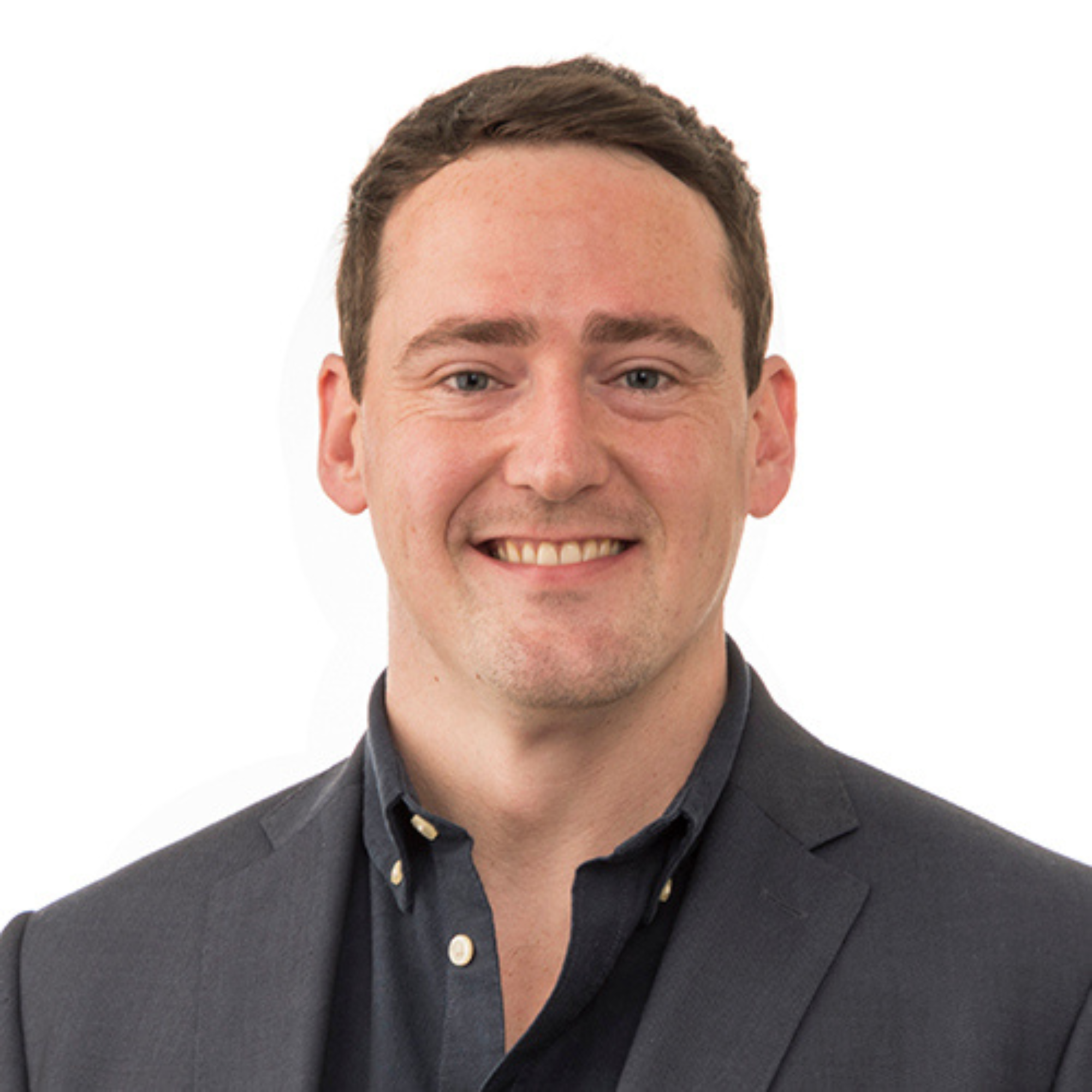 Headshot of a smiling man with short brown hair wearing a dark blazer and a dark collared shirt.