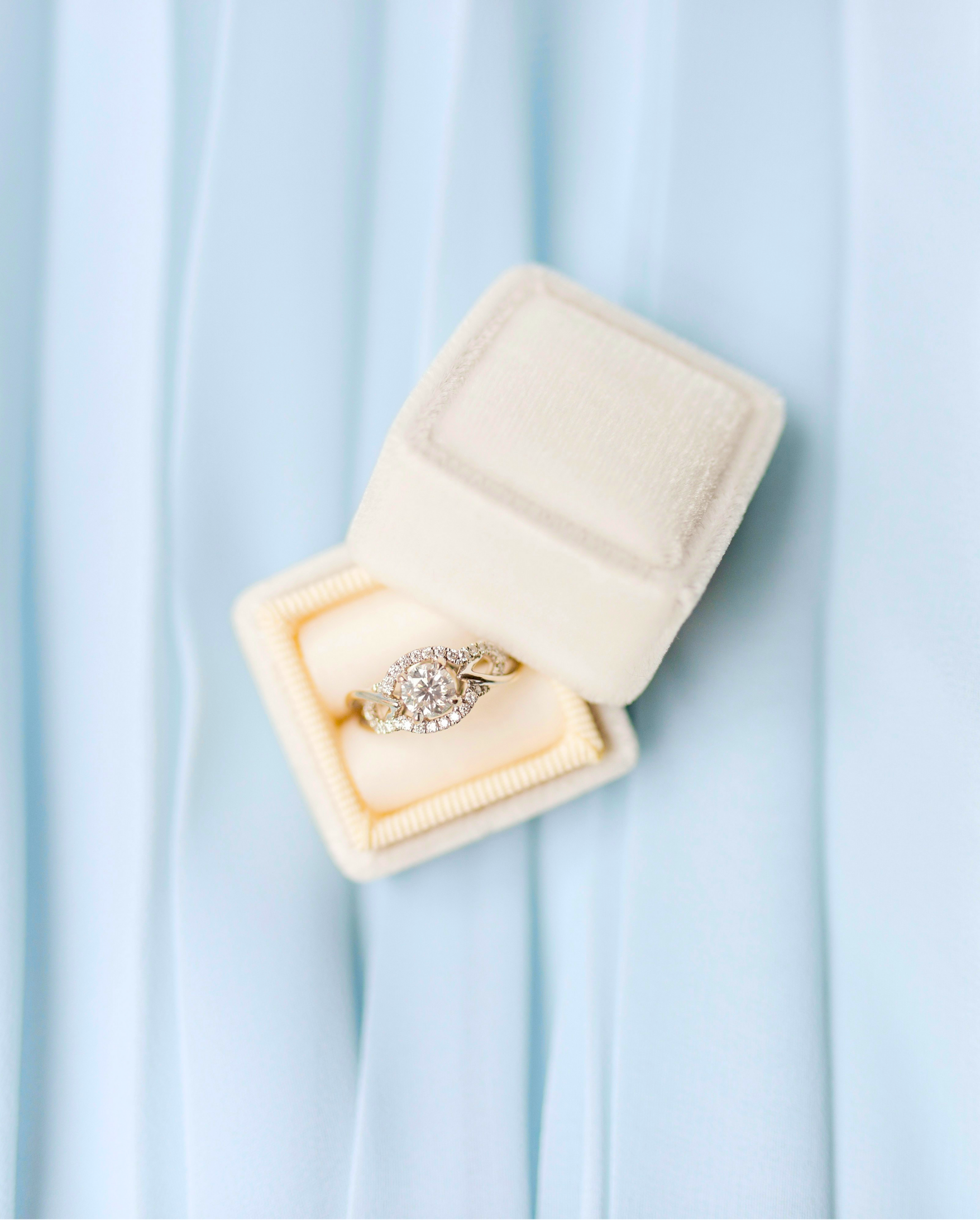 Diamond ring in a white velvet box on light blue fabric