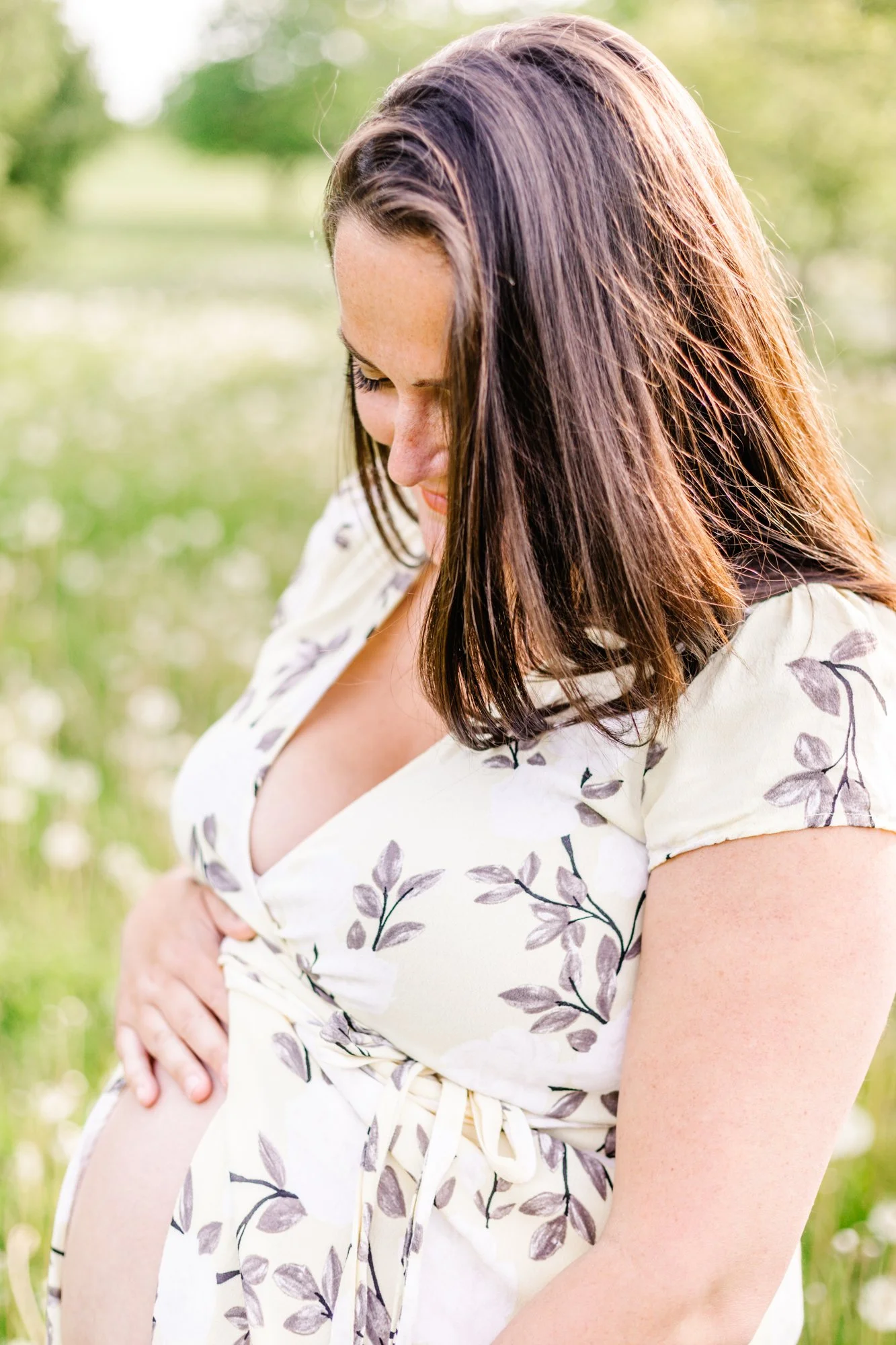 Pregnant woman in floral dress holding her belly
