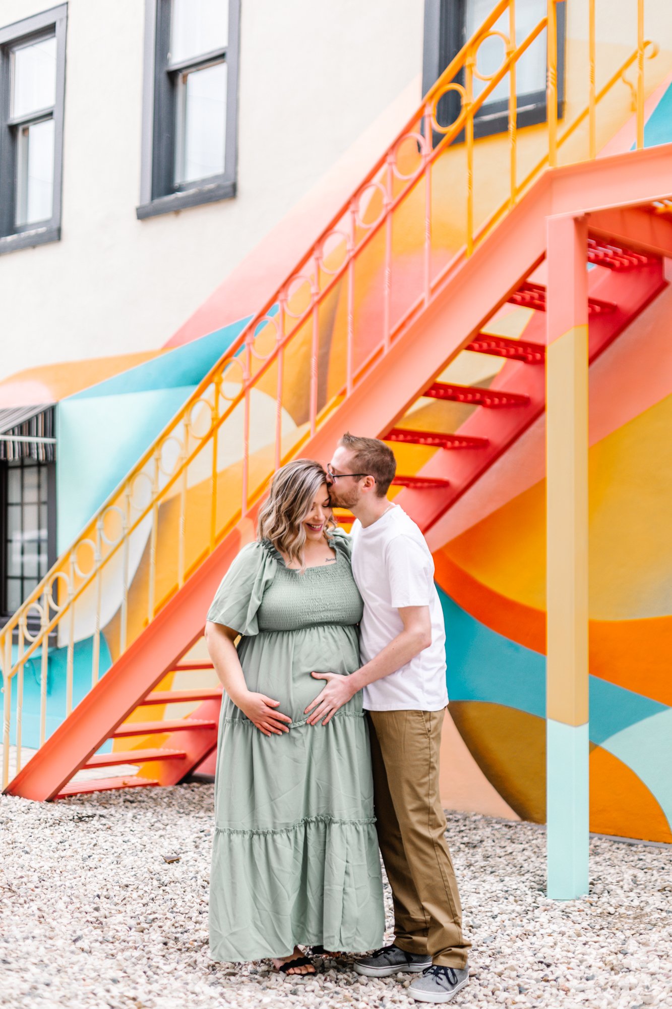Pregnant woman and man standing affectionately by colorful staircase