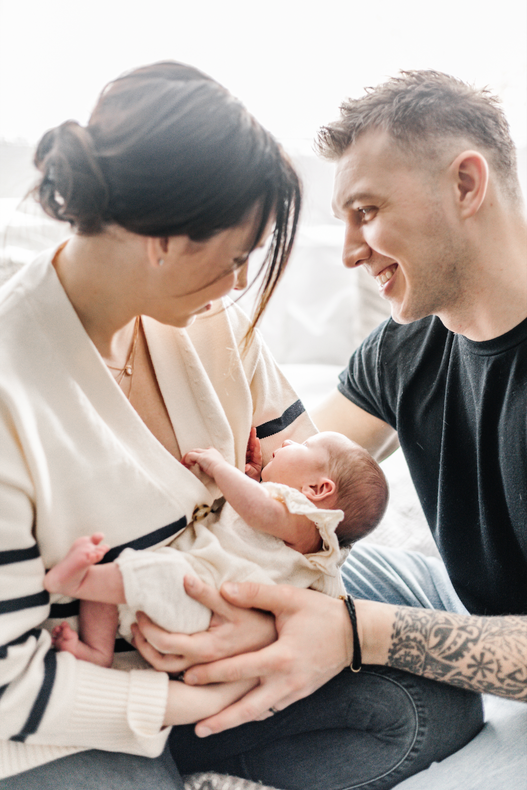 A couple smiling at their newborn baby.