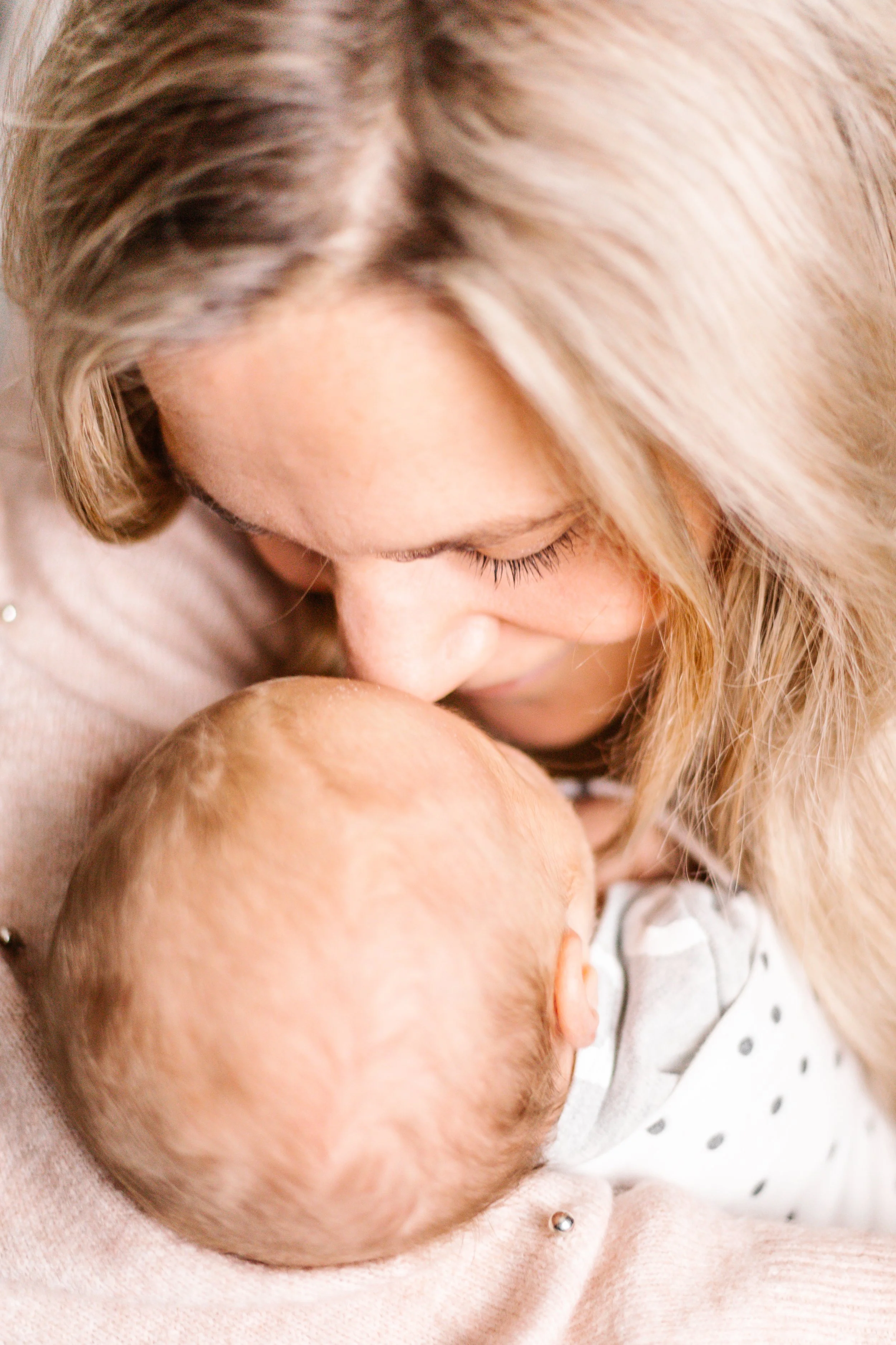 Close-up of a woman gently cuddling a baby.