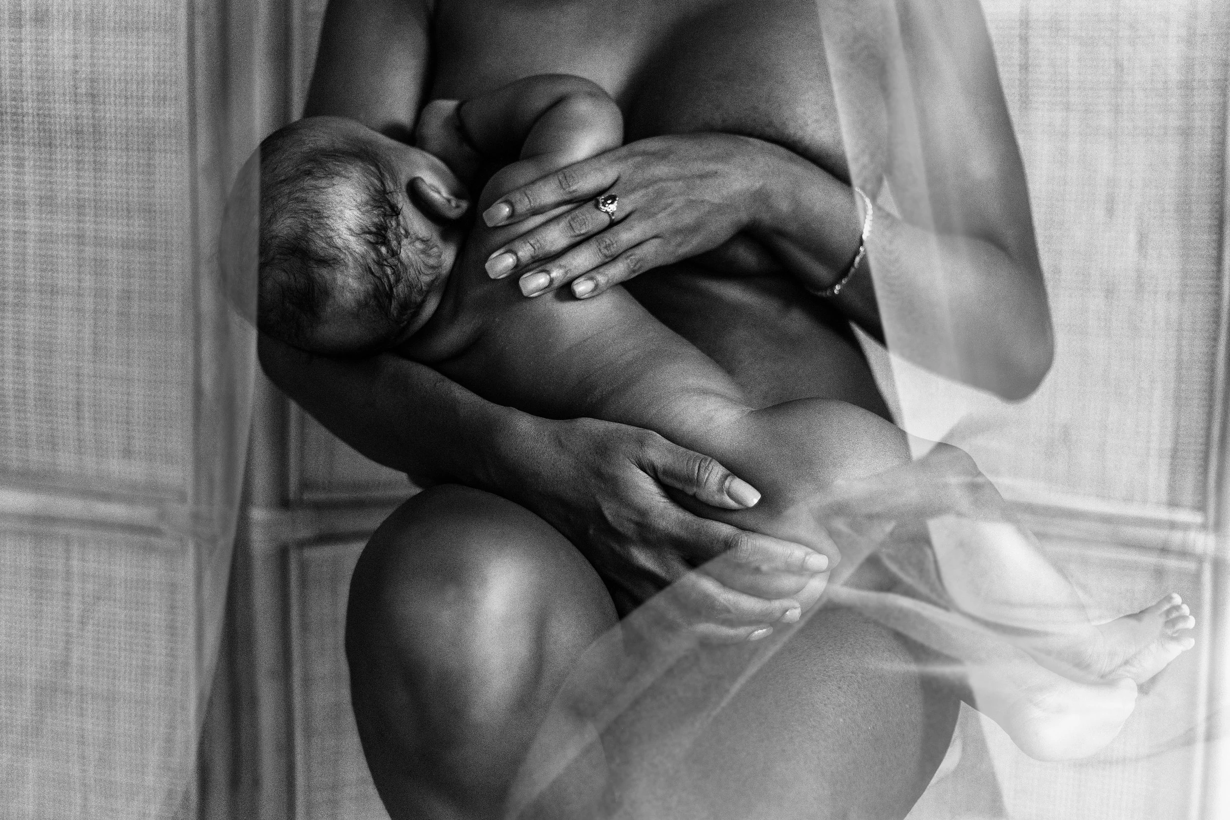 Black and white photo of a mother breastfeeding a baby while sitting.