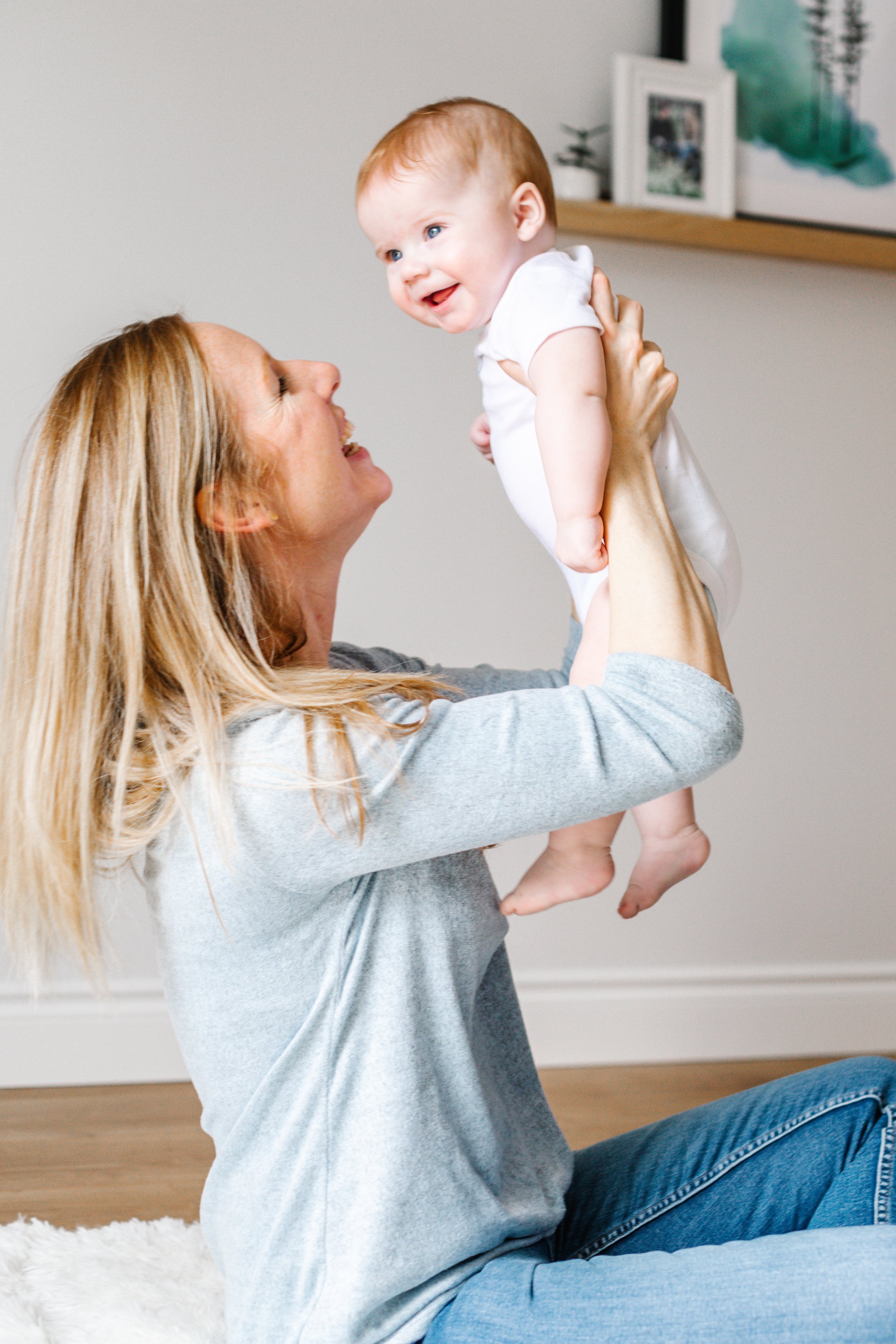Woman holding smiling baby, indoor setting, bonding moment