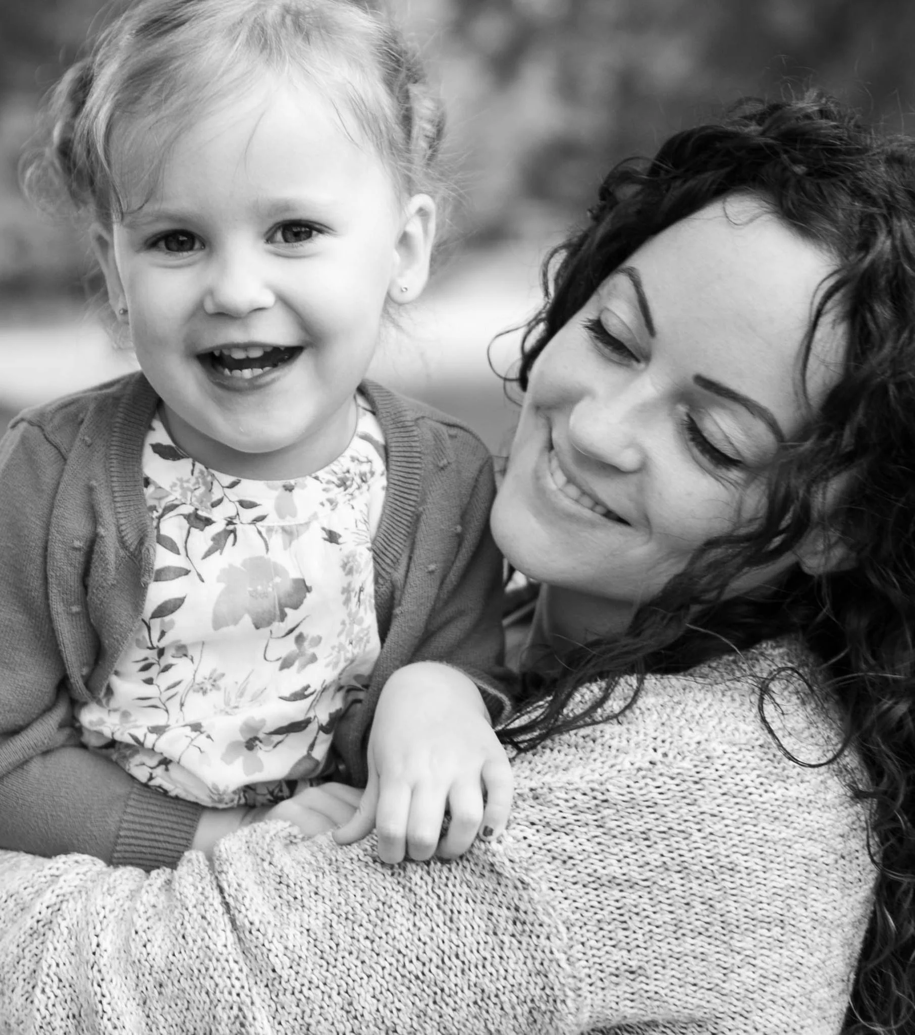 Black and white photo of a smiling woman holding a young girl.