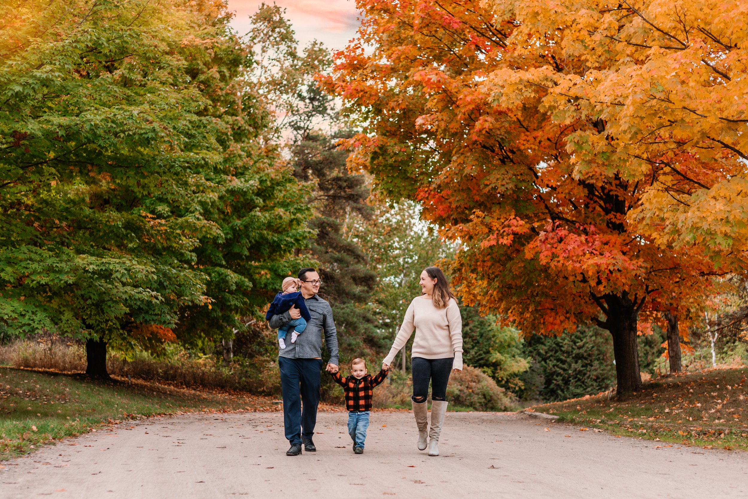 Family walking on a path surrounded by colorful autumn trees.