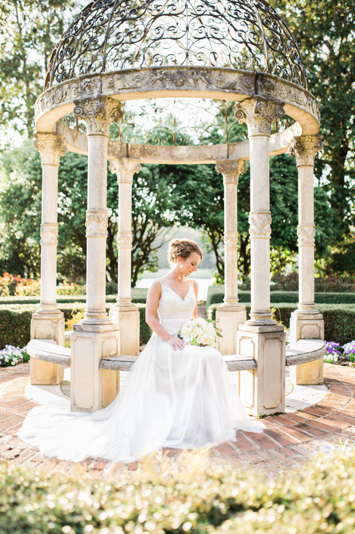 Bride sitting under gazebo, holding bouquet