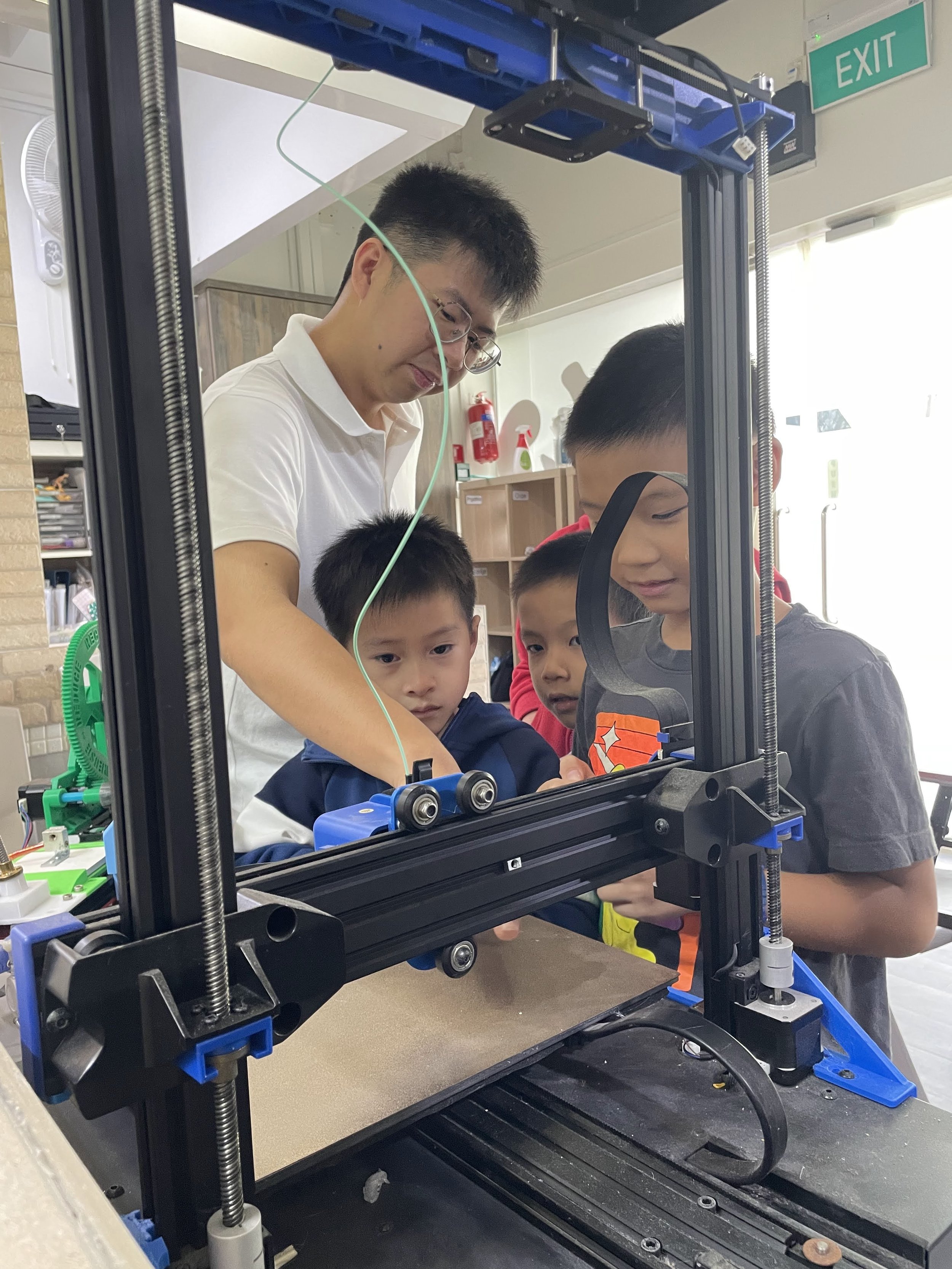 Children observing a 3D printer creating a prototype during a hands-on STEM workshop