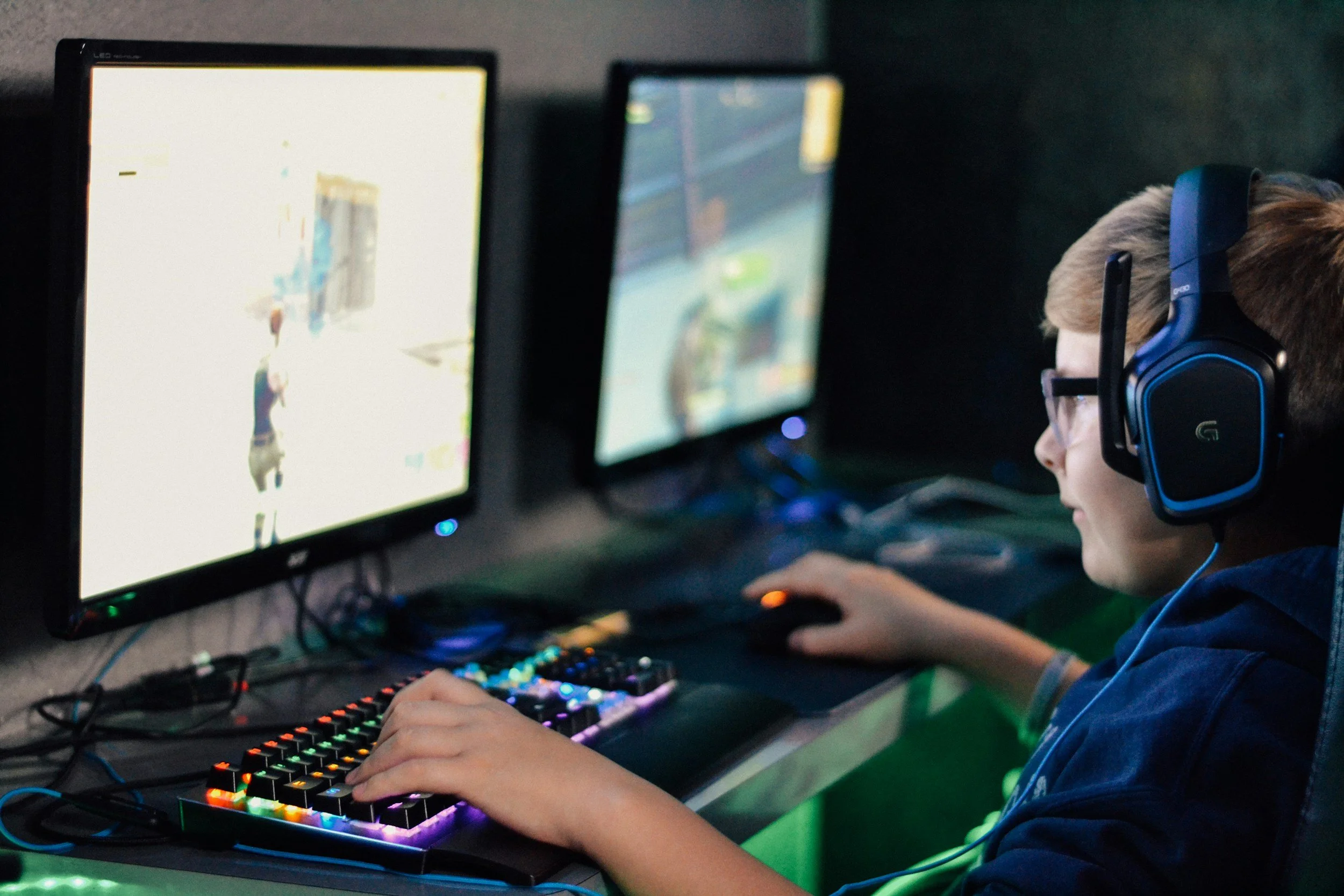 Child playing a video game at a multi-screen gaming setup with a headset