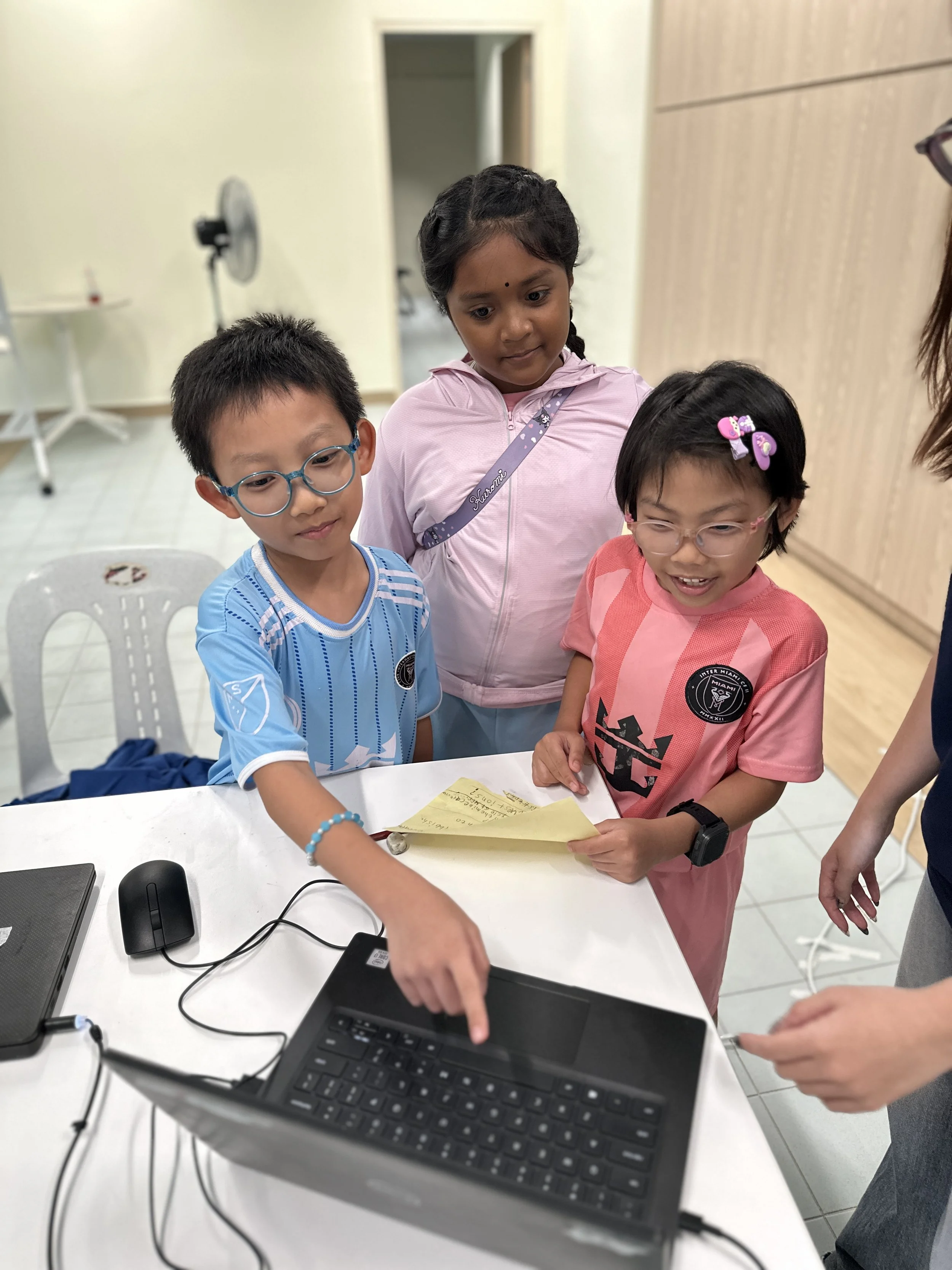 Children collaborating around a laptop and handwritten notes during a Community STEM problem-solving activity